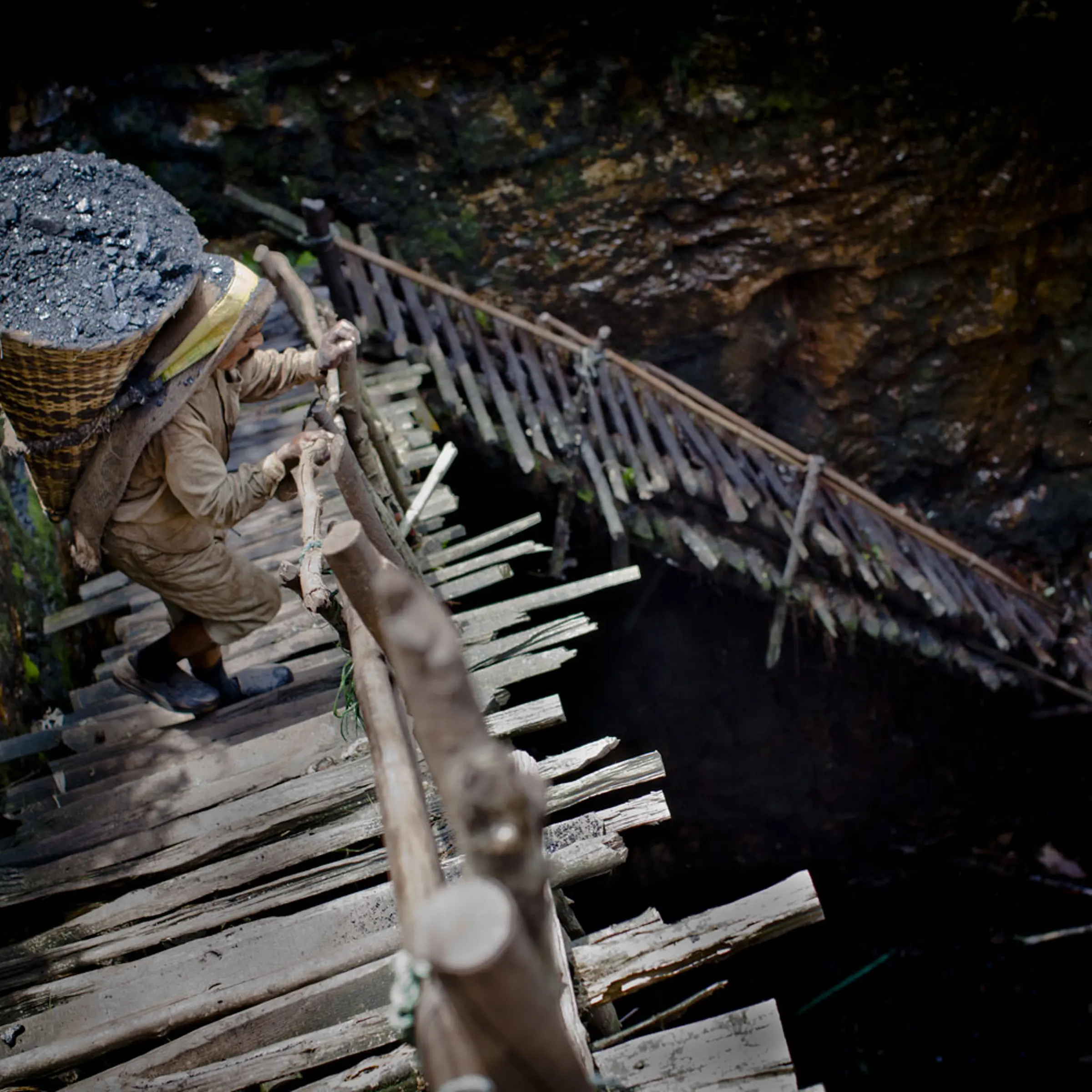 Prabhat Sinha, from Assam, carries a load of coal weighing 60kg's, supported by a head-strap, as he ascends the staircase of a coal mine near the village of Khliehriat, in the district of Jaintia Hills, India. miners descend to great depths on slippery, rickety wooden ladders. Children and adults squeeze into rat hole like tunnels in thousands of privately owned and unregulated mines, extracting coal with their hands or primitive tools and no safety equipment.