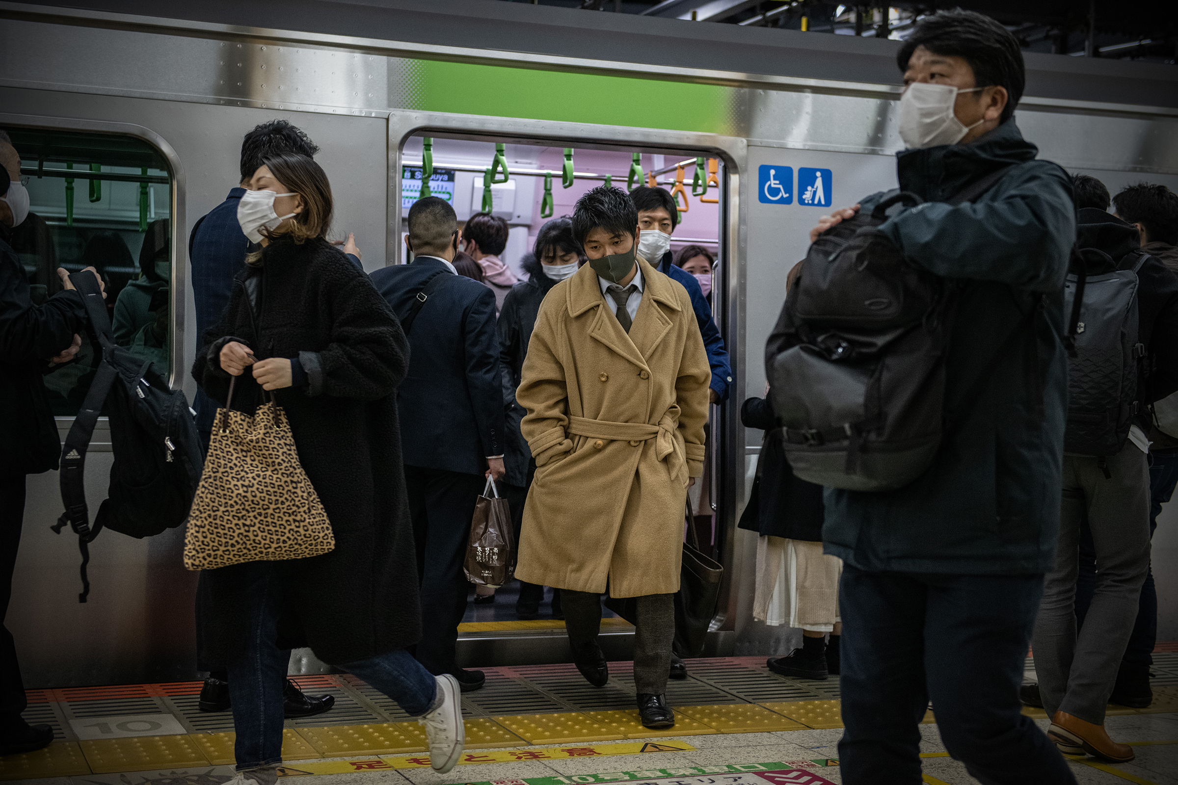People wearing face masks disembark a Yamanote Line train on Dec. 16 in Tokyo