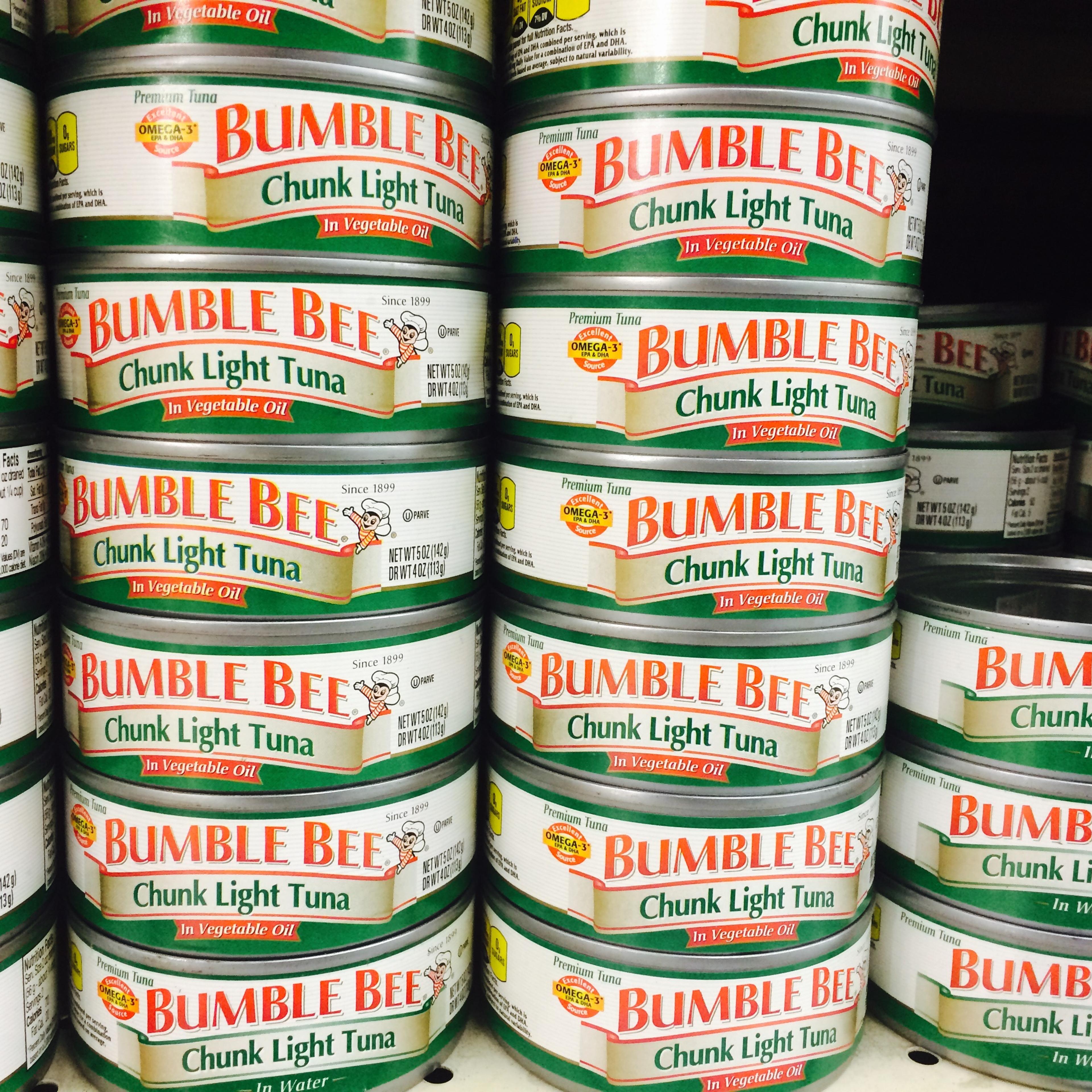 Bumble Bee chunk light tuna can is seen on a shelf at a grocery store.