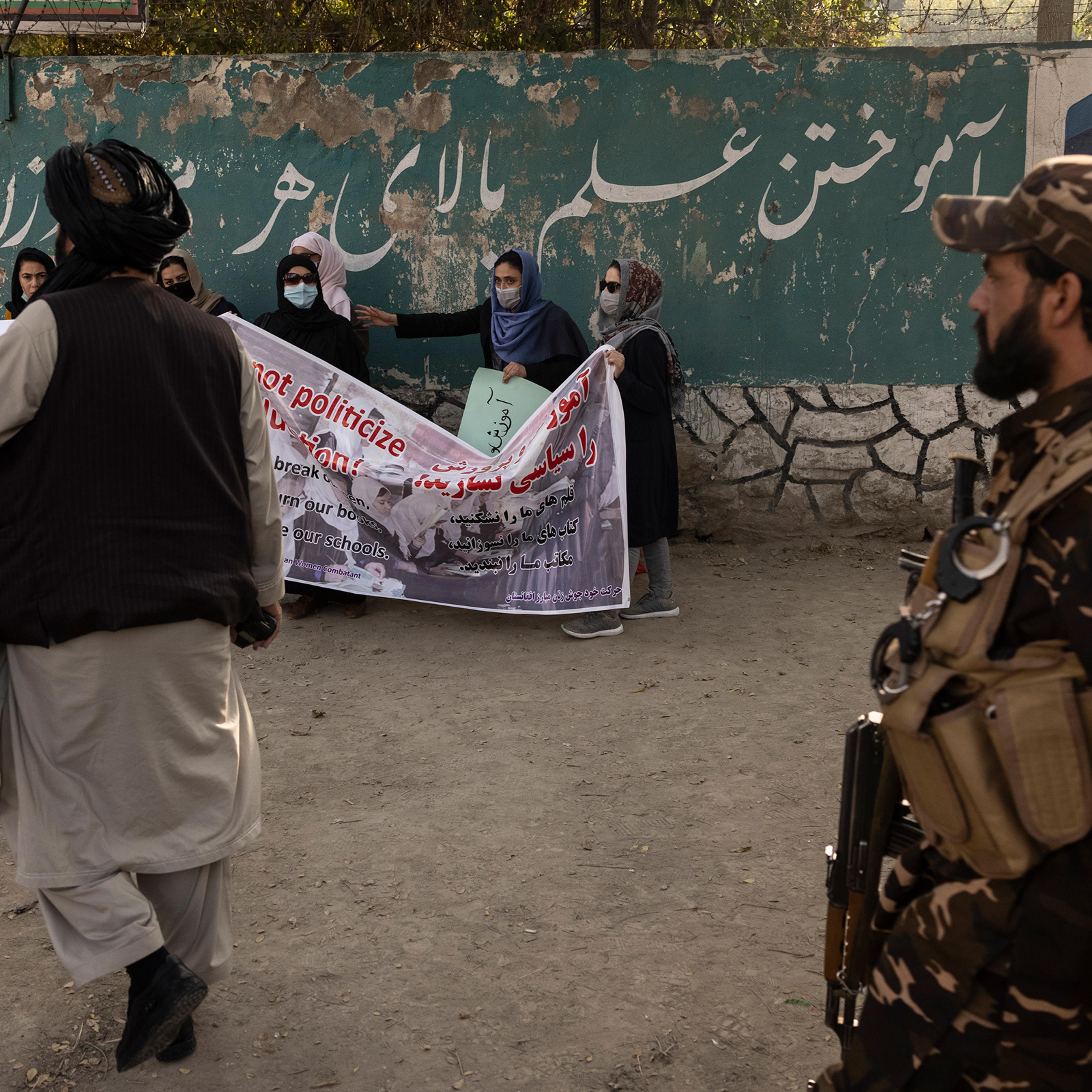 Taliban members disperse a small group of women rallying in support of women's education outside a girls high school in Kabul on Sept. 30.