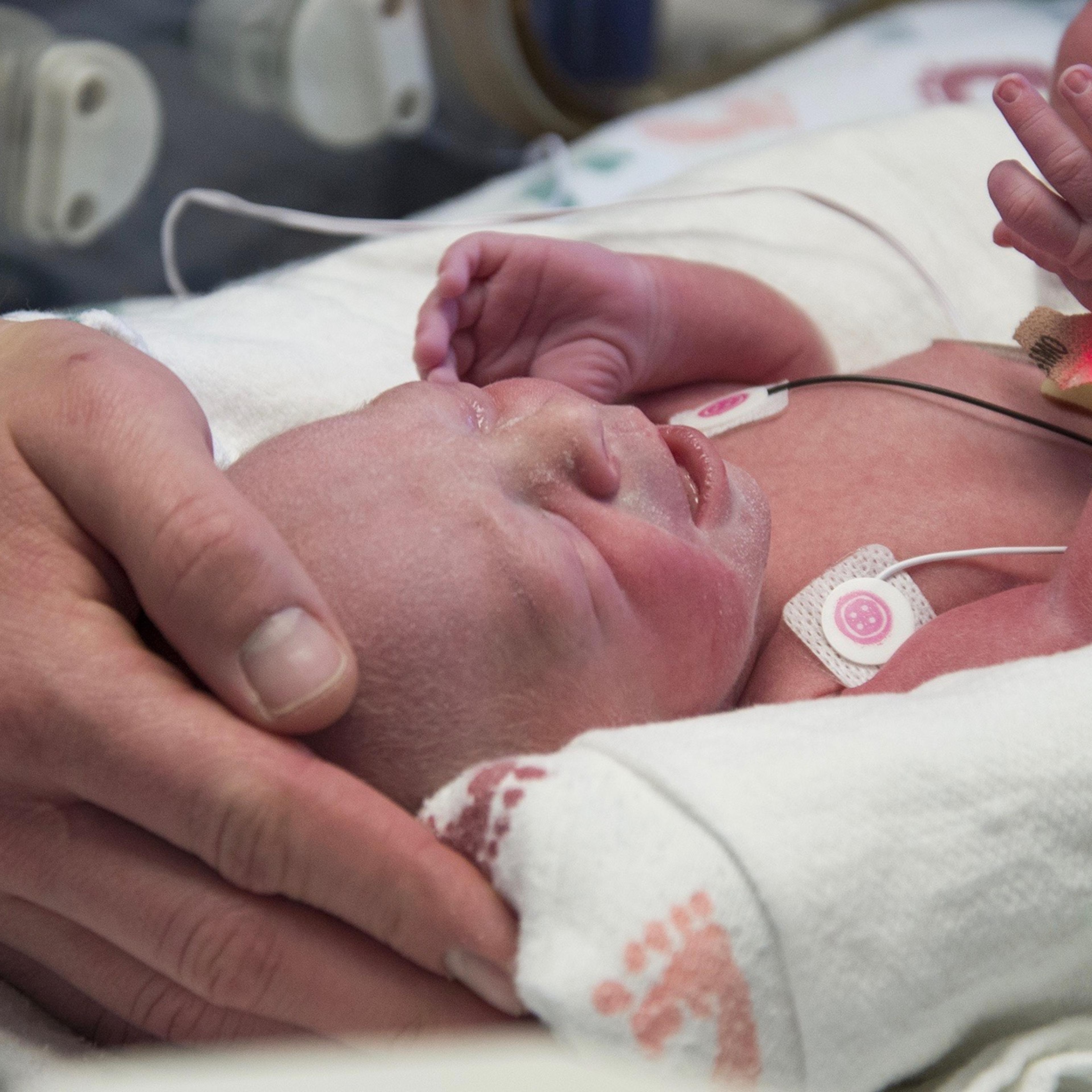 The baby's father rests his hand on the child.