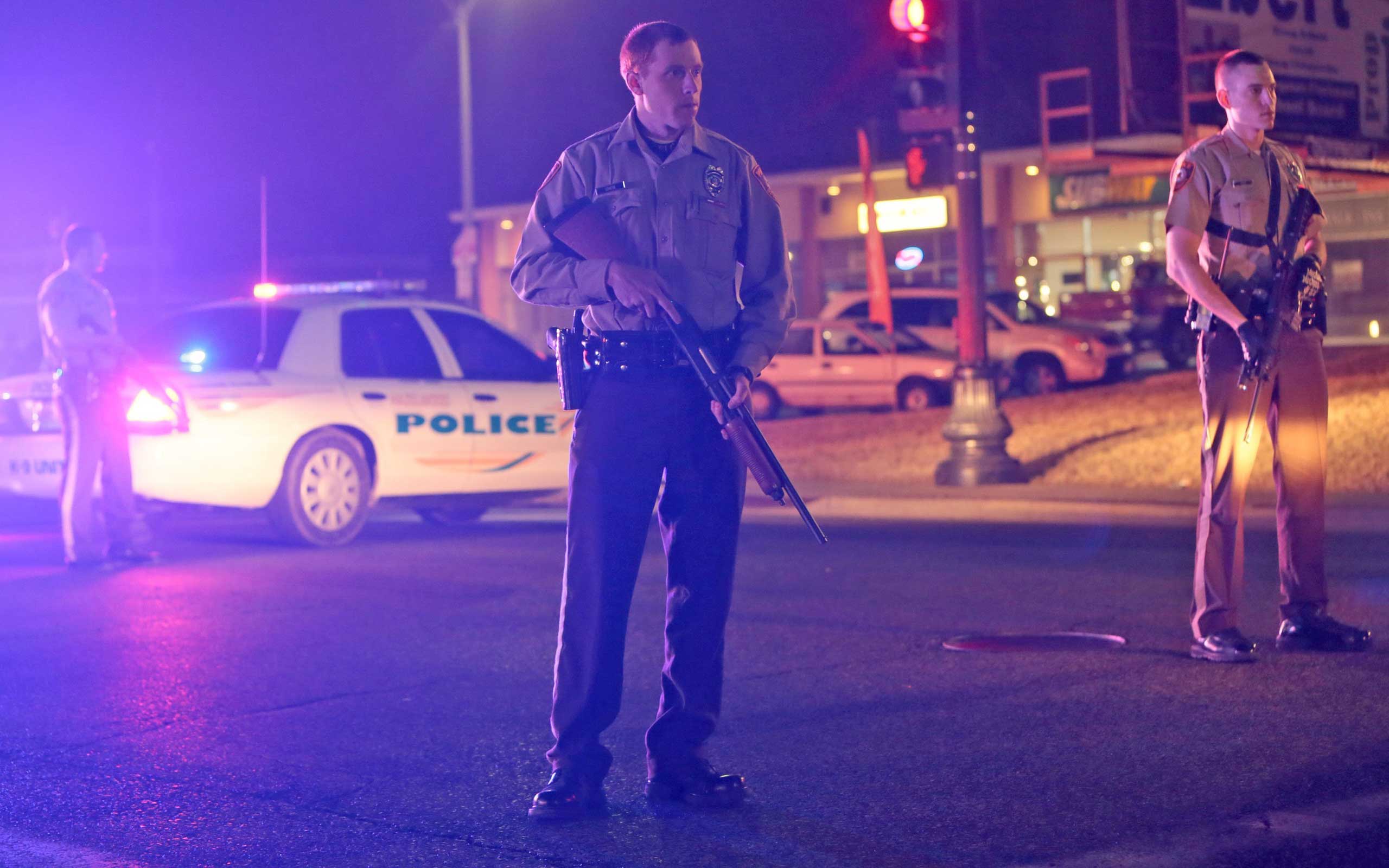 Police guard the corner off Adams Street and South Florissant Rd after two officers were shot while standing guard in front of the Ferguson Police Station on March 12, 2015.