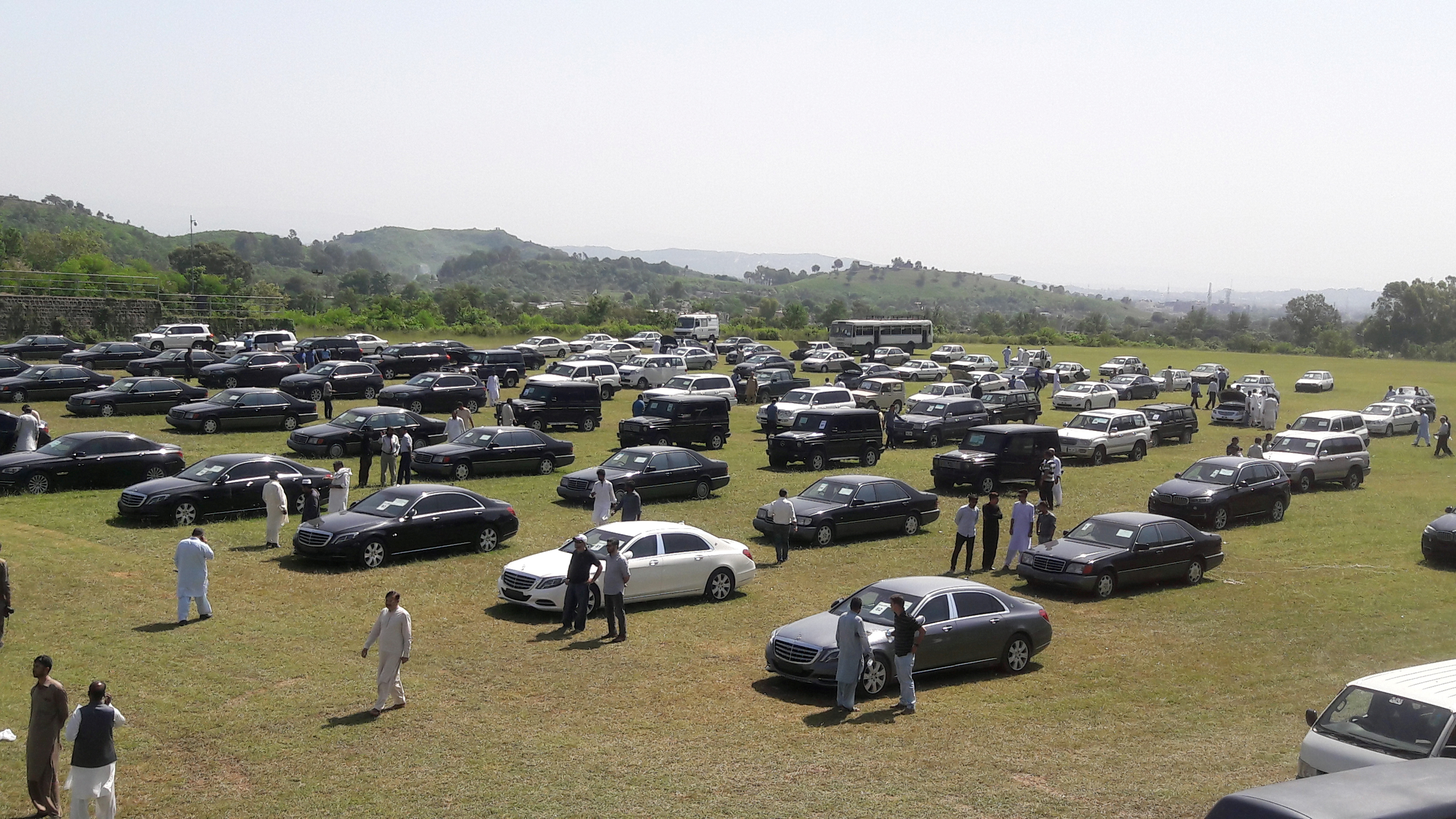 People visit an auction of government owned used cars at the premises of Prime Minister House in Islamabad
