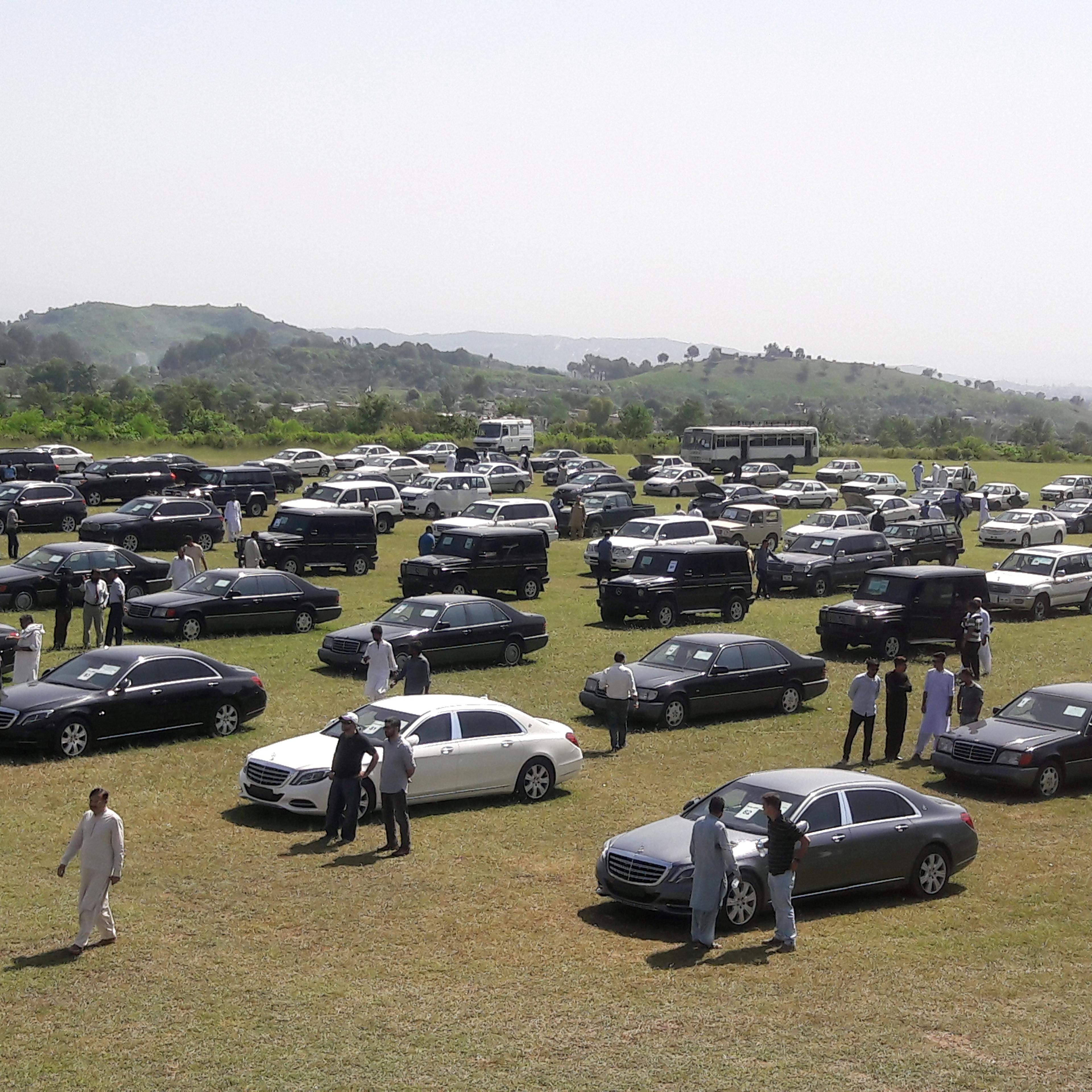 People visit an auction of government owned used cars at the premises of Prime Minister House in Islamabad