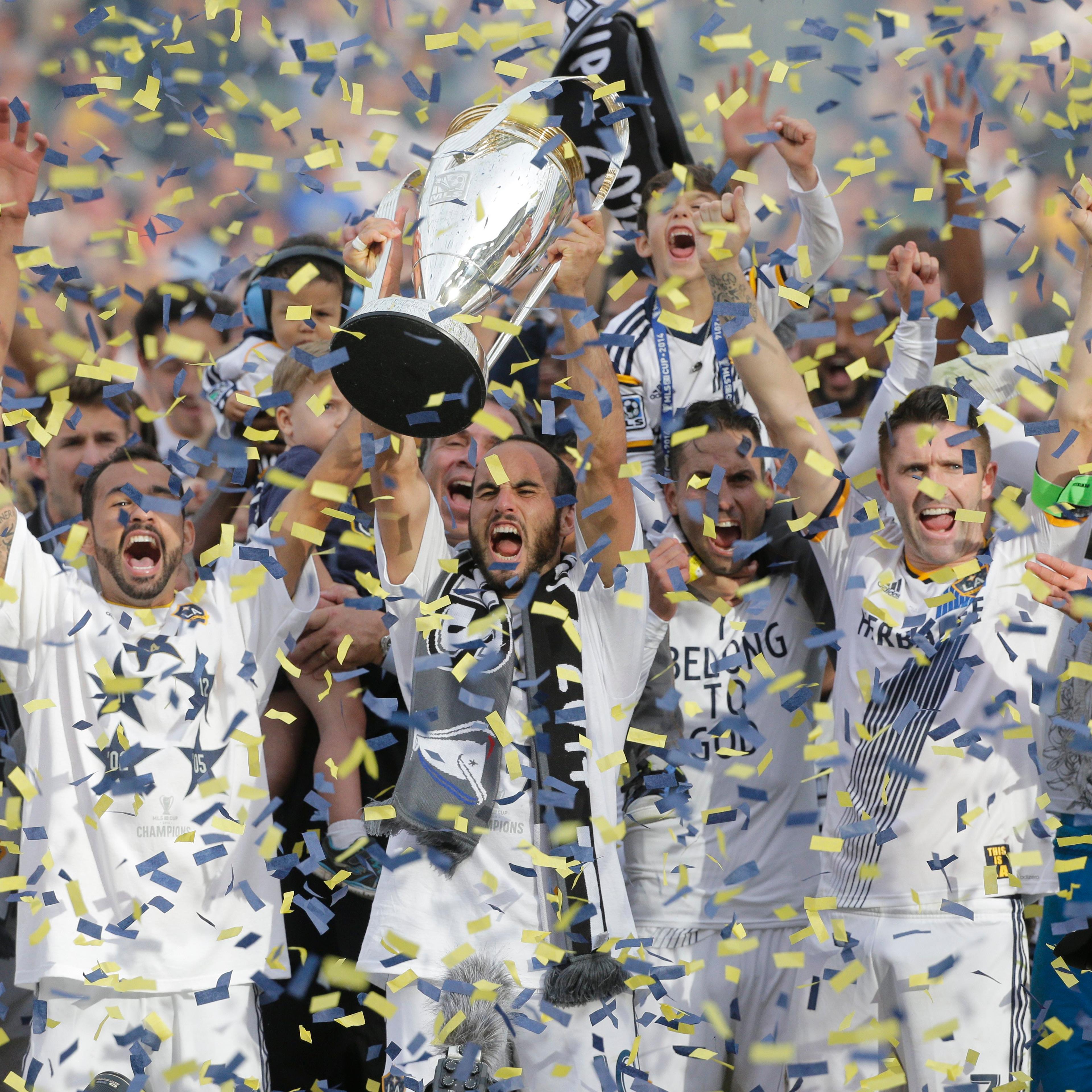 Los Angeles Galaxy's Landon Donovan hoists the trophy as he and teammates celebrate after winning the MLS Cup championship soccer match against the New England Revolution on Dec. 7, 2014, in Carson, Calif.