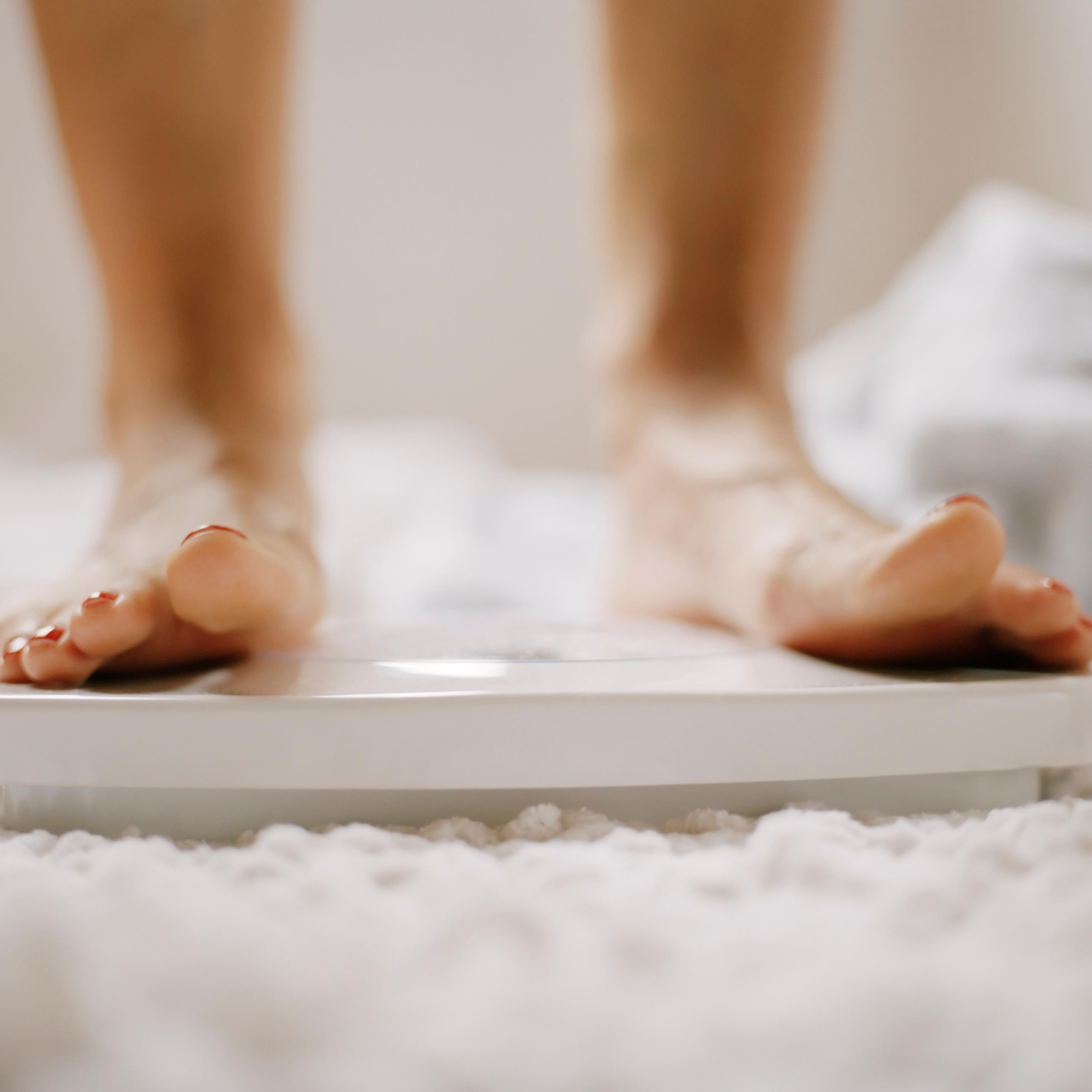 Close-up of woman's feet on scale TIME health stock
