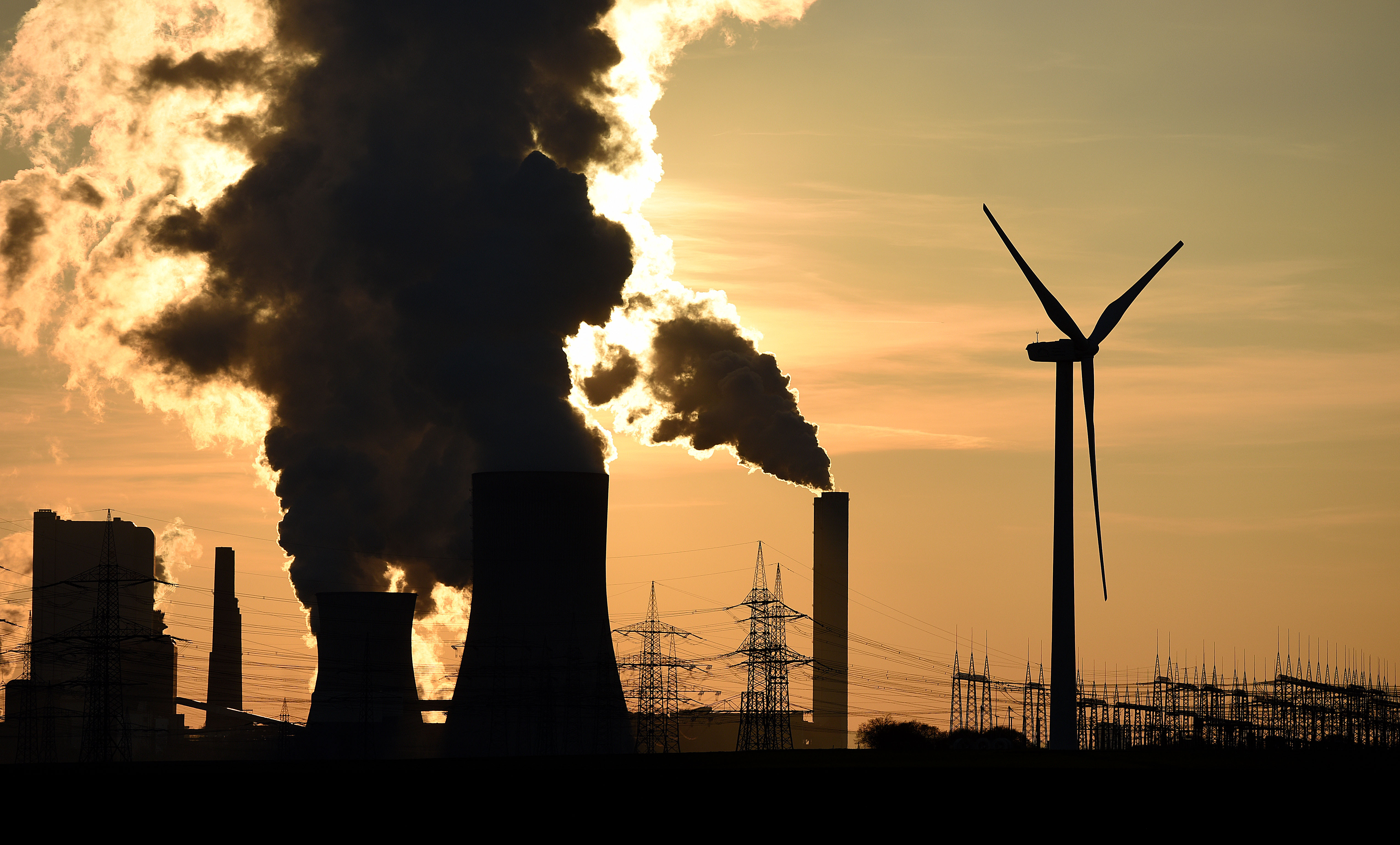 Electricity pylons and wind turbines stand beside the RWE Niederaussem coal-fired power plant while Steam rises from cooling towers on February 16, 2016 near Bergheim, Germany.