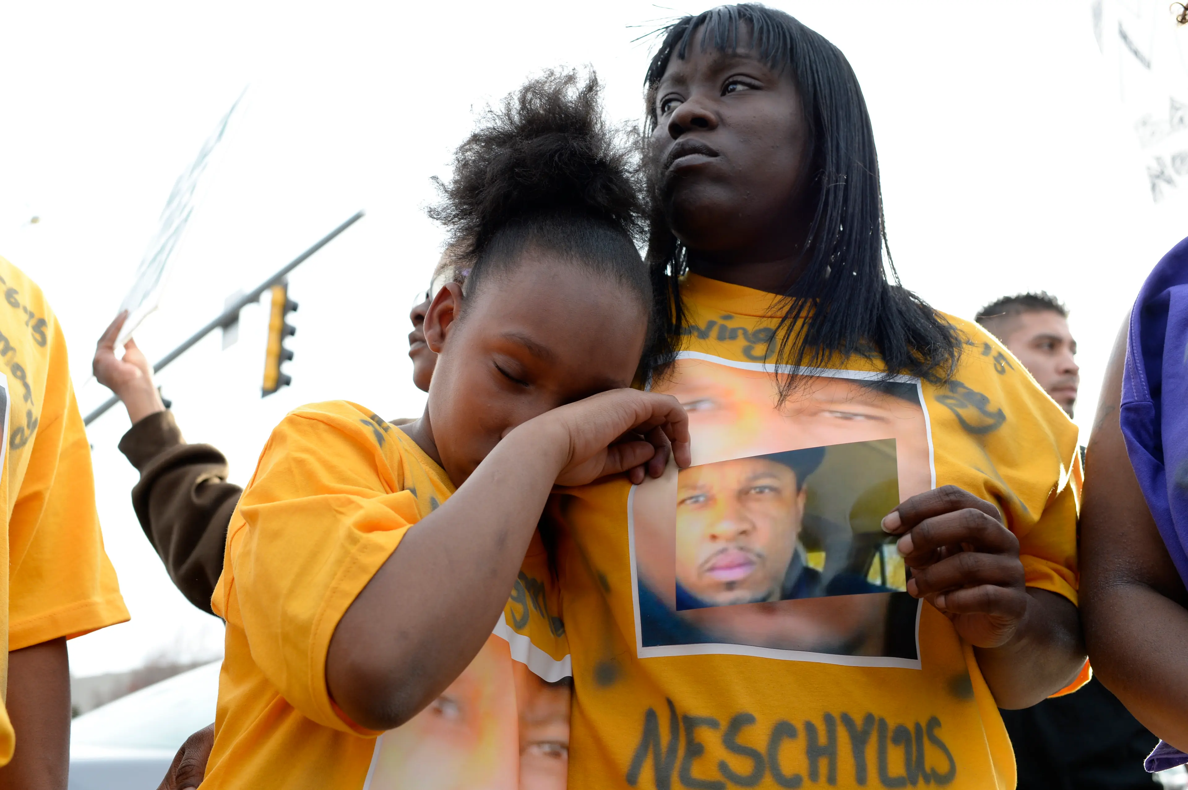 Xiaxong Carter, 10, daughter of Naeschylus Vinzant, wipes away a tear while she holds onto her mother, Laneisha Butler during a protest against the fatal police shooting of her father, in Aurora, Colo. on March 11, 2015.
