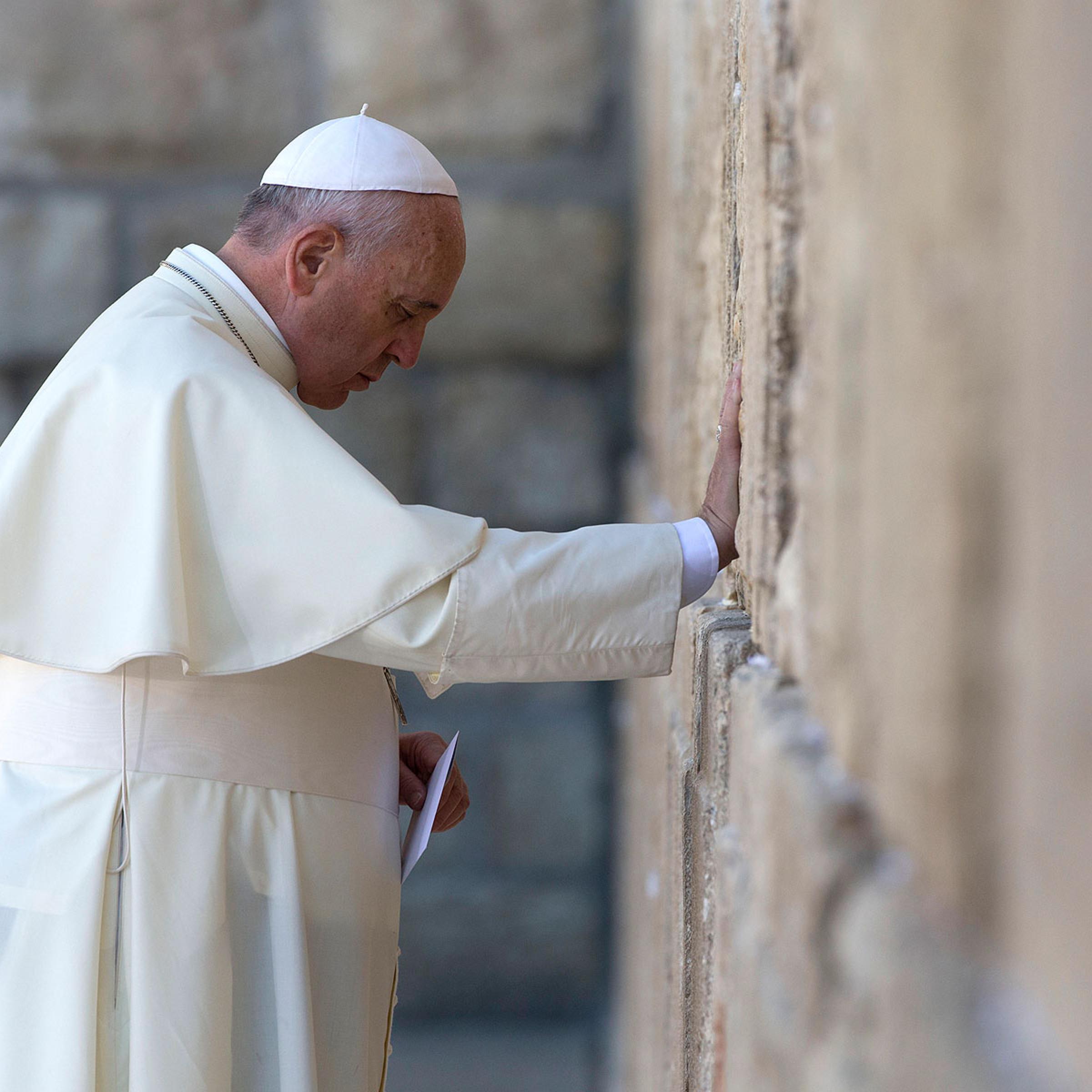Pope Francis prays as he holds an envelope before placing it in one of the cracks between the stones of the Western Wall, the holiest place where Jews can pray, in Jerusalem on May 26, 2014