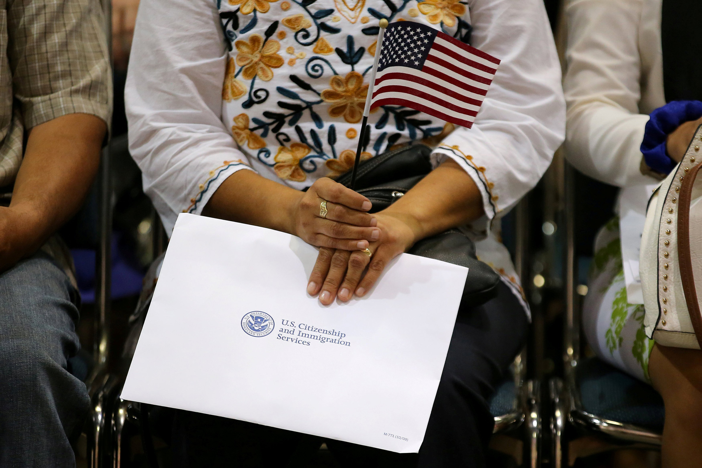 An attendee holds her new country's flag and her naturalization papers as she is sworn in during a U.S. citizenship ceremony