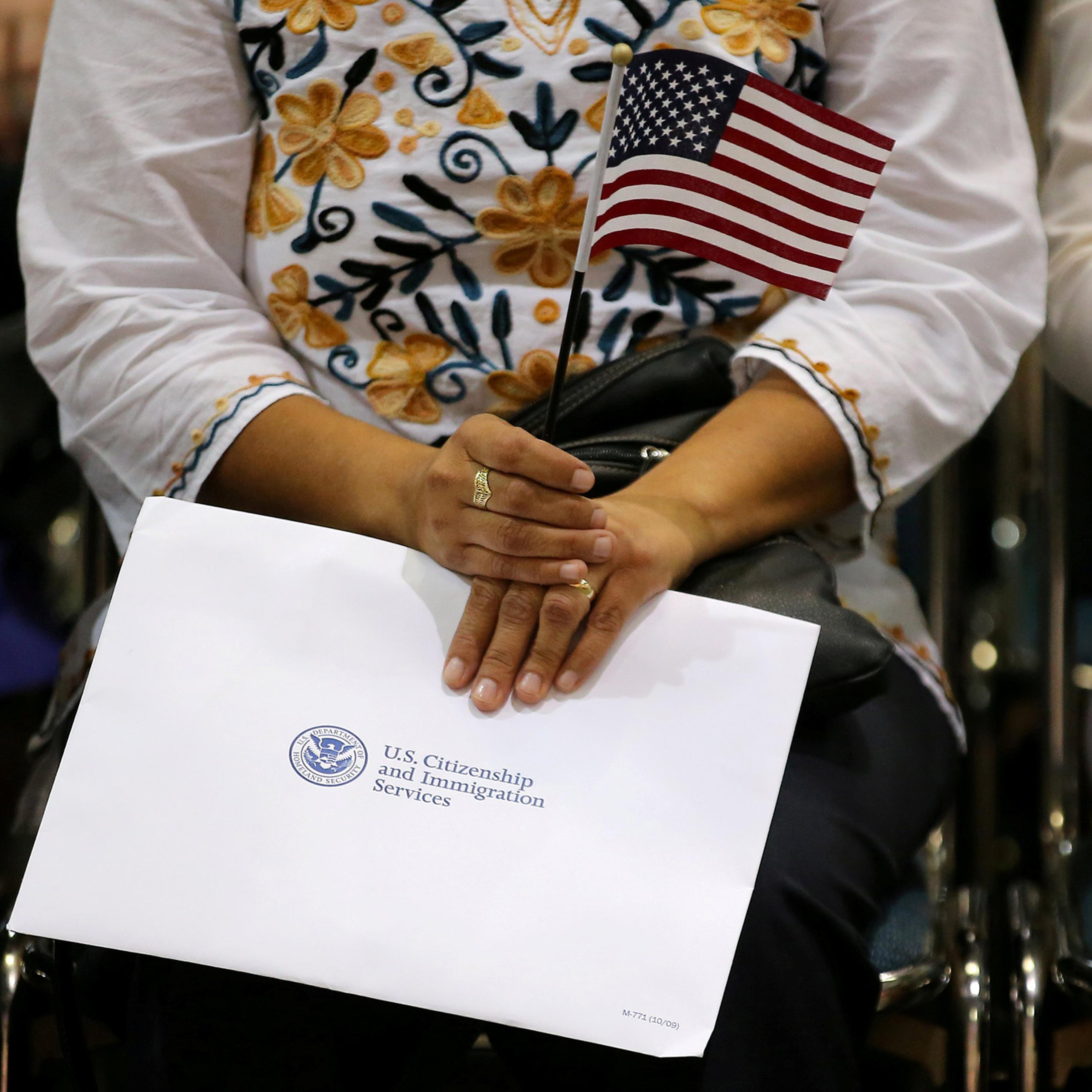 An attendee holds her new country's flag and her naturalization papers as she is sworn in during a U.S. citizenship ceremony