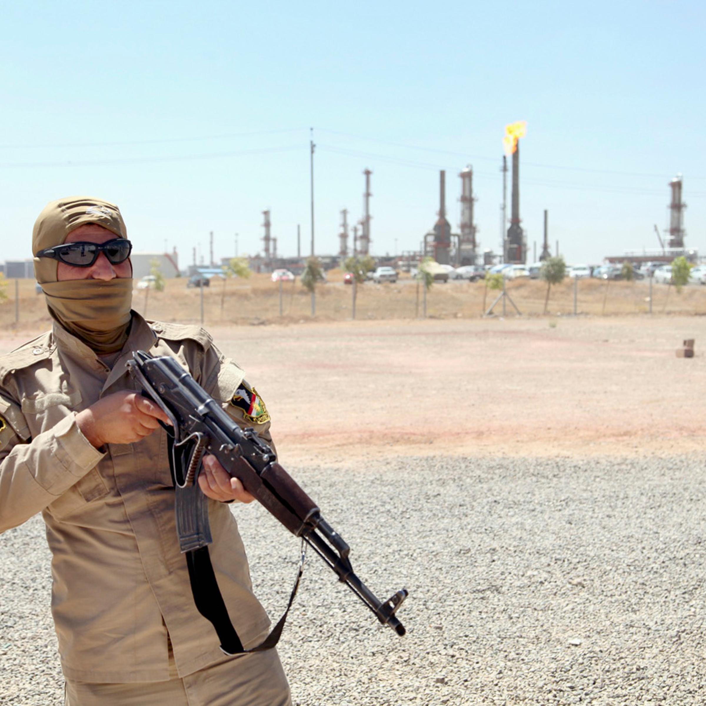 A member of Kurdish security forces takes up position with his weapon as he guards an oil refinery on the outskirts of Mosul