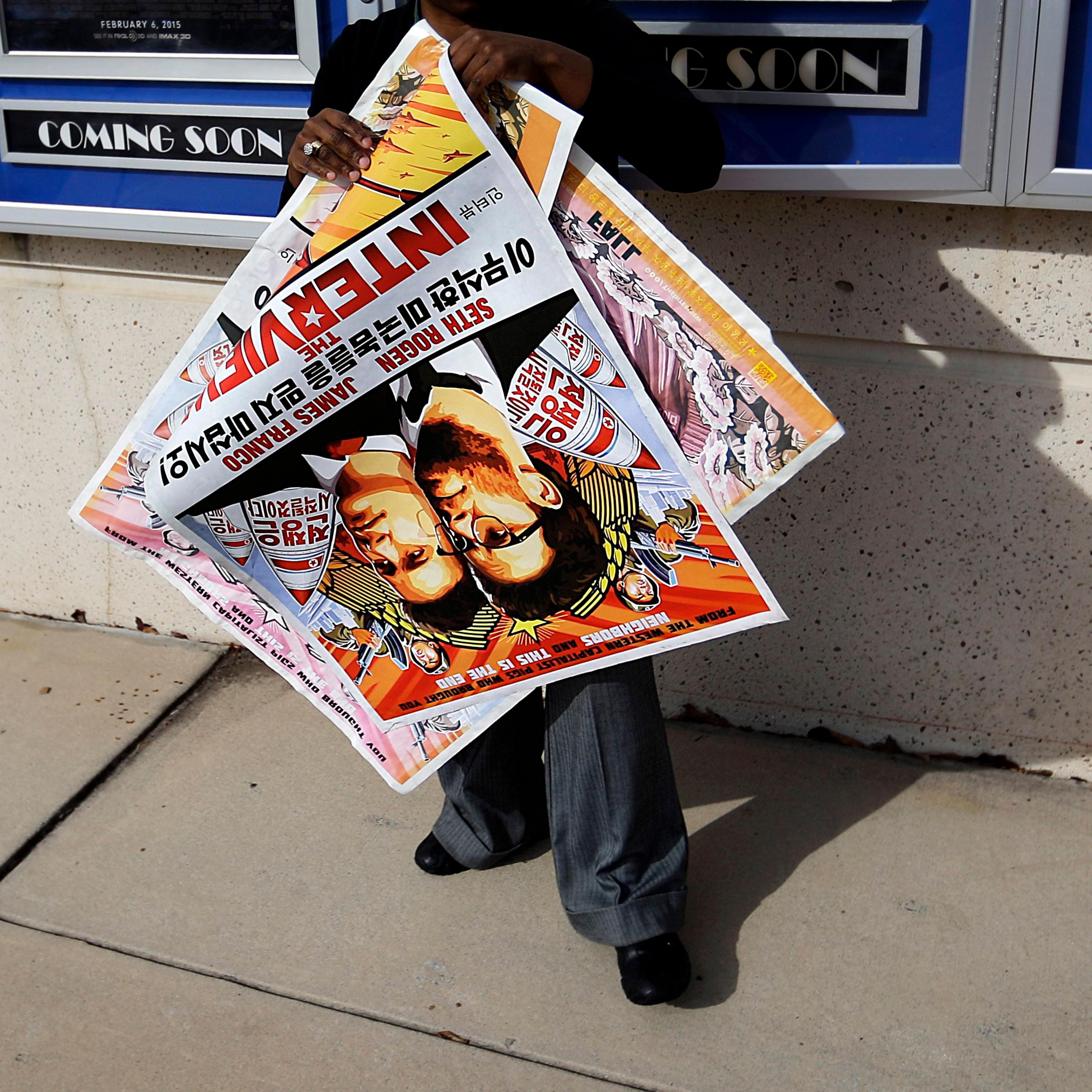 A poster for the movie "The Interview" is carried away by a worker after being pulled from a display case at a Carmike Cinemas movie theater on Dec. 17, 2014, in Atlanta.