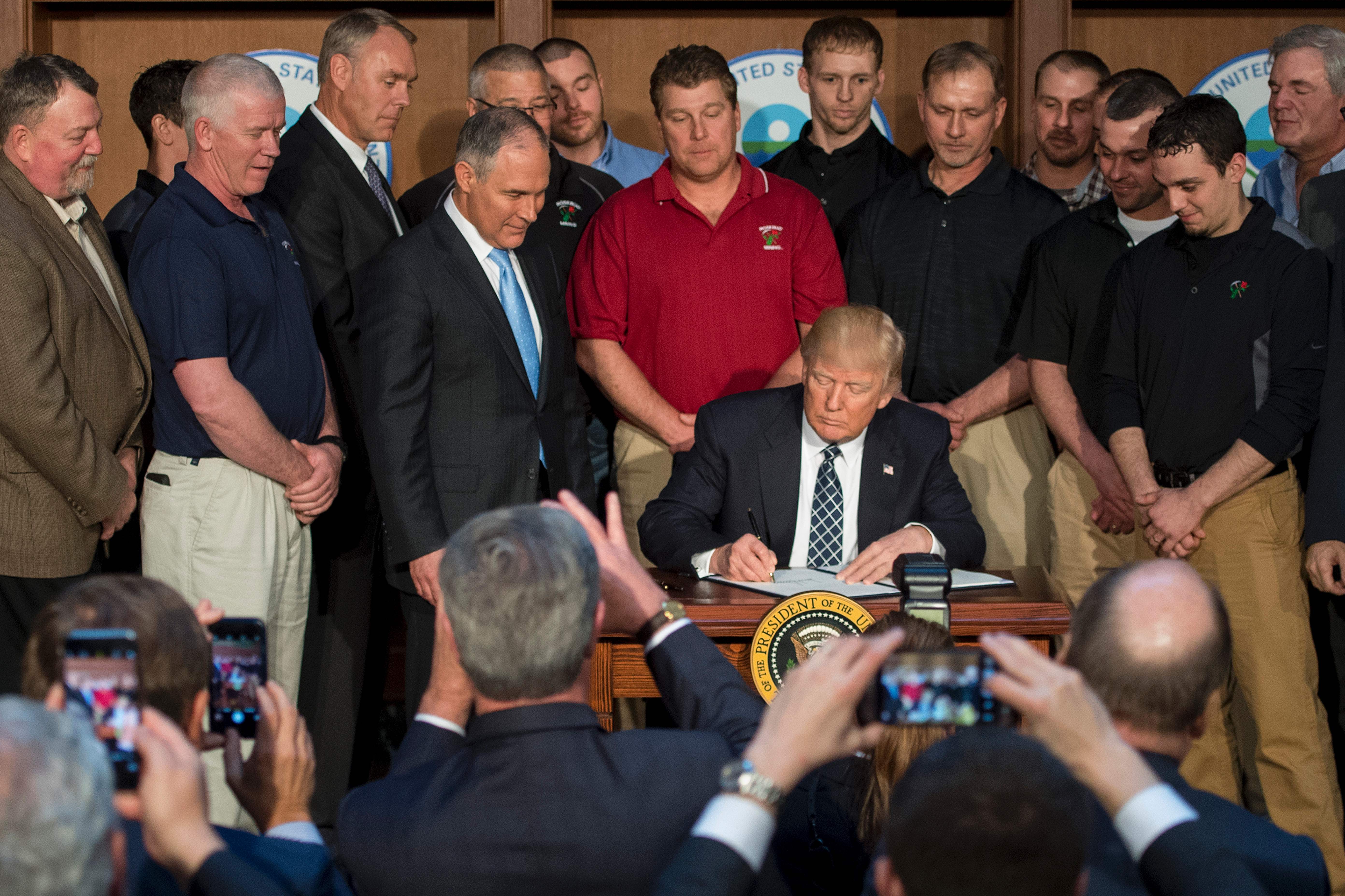 Surrounded by miners, President Donald Trump signs the Energy Independence Executive Order at the Environmental Protection Agency (EPA) Headquarters in Washington, DC, March 28, 2017.Although the administration has moved aggressively to curtail Obama era