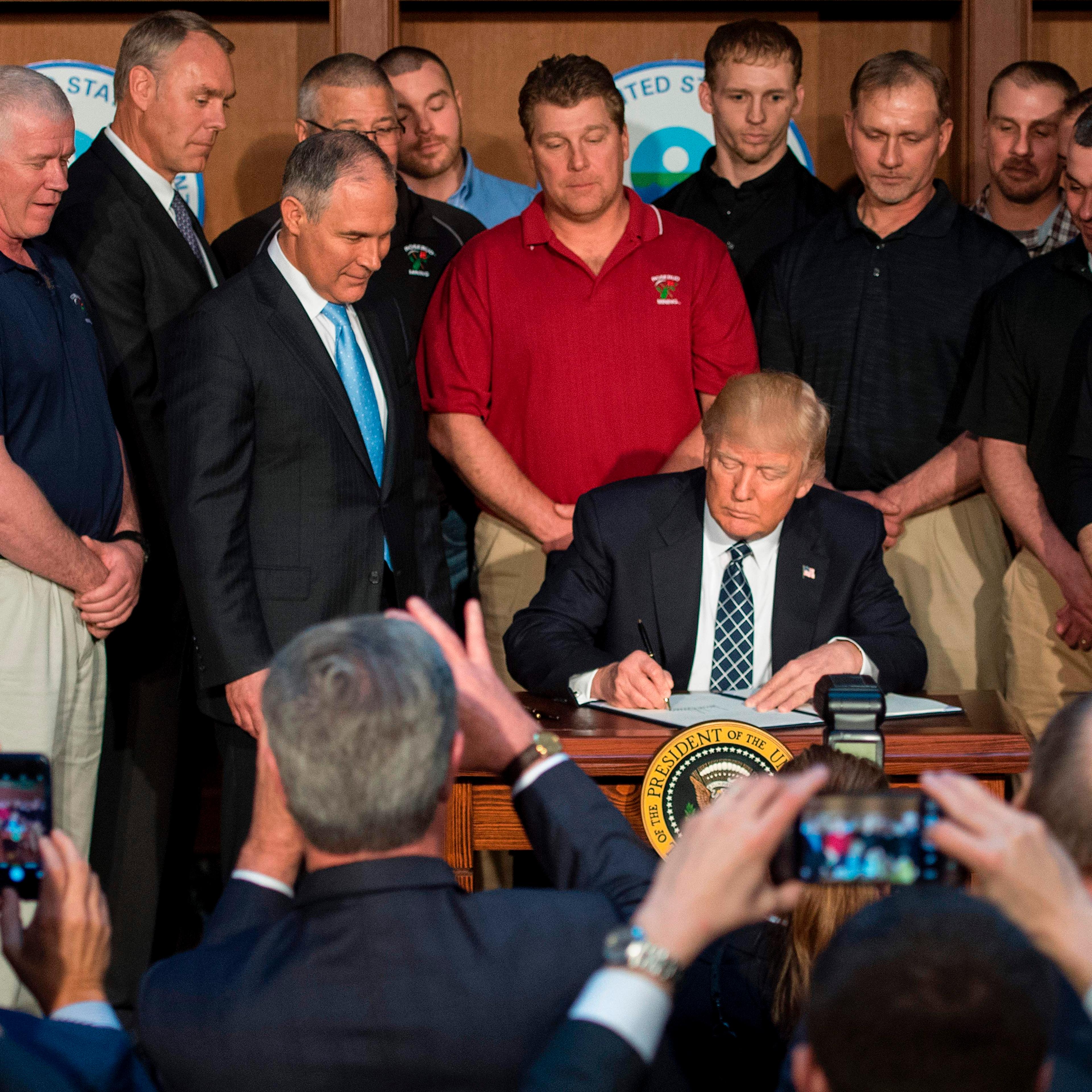 Surrounded by miners, President Donald Trump signs the Energy Independence Executive Order at the Environmental Protection Agency (EPA) Headquarters in Washington, DC, March 28, 2017.Although the administration has moved aggressively to curtail Obama era