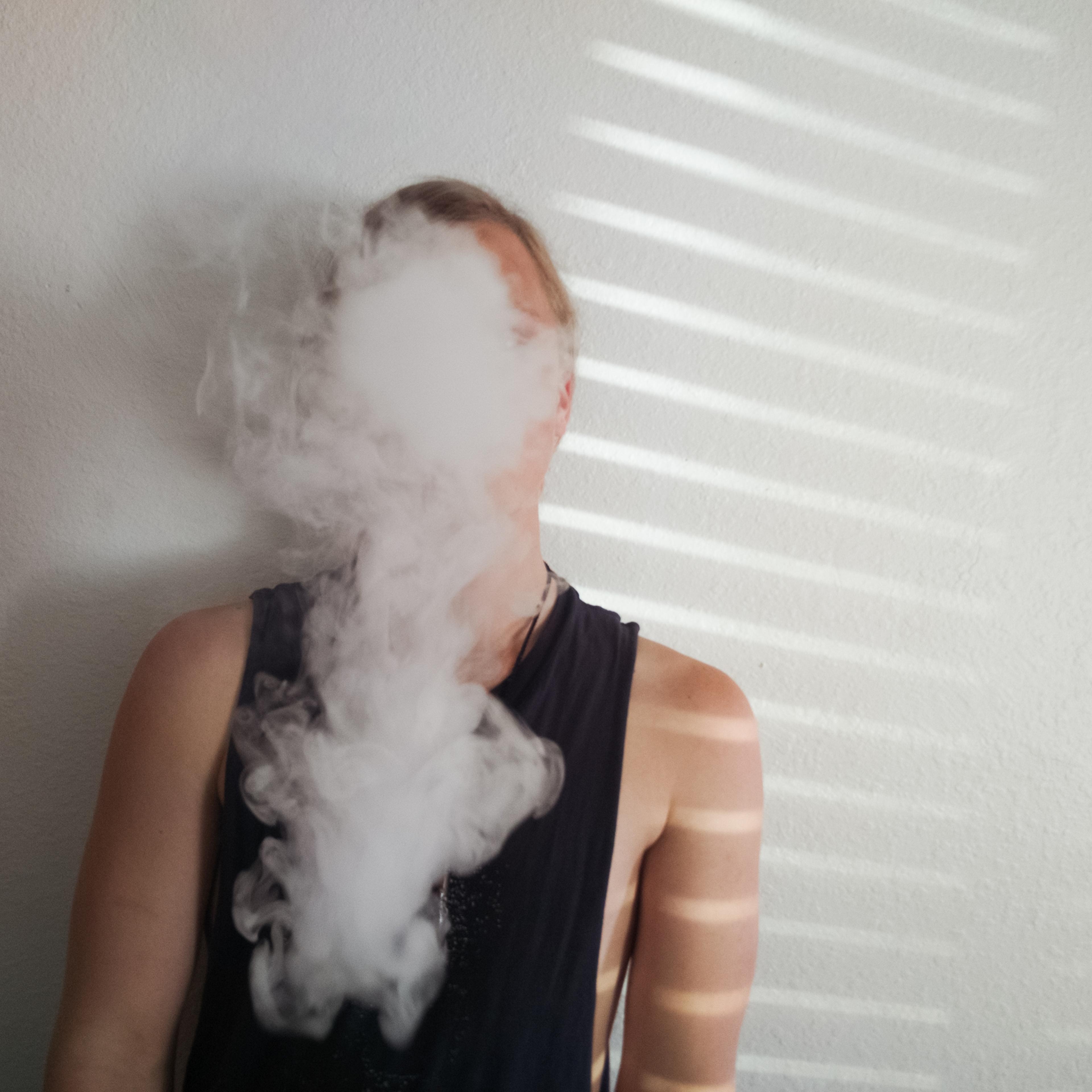 Young man vaping by a wall
