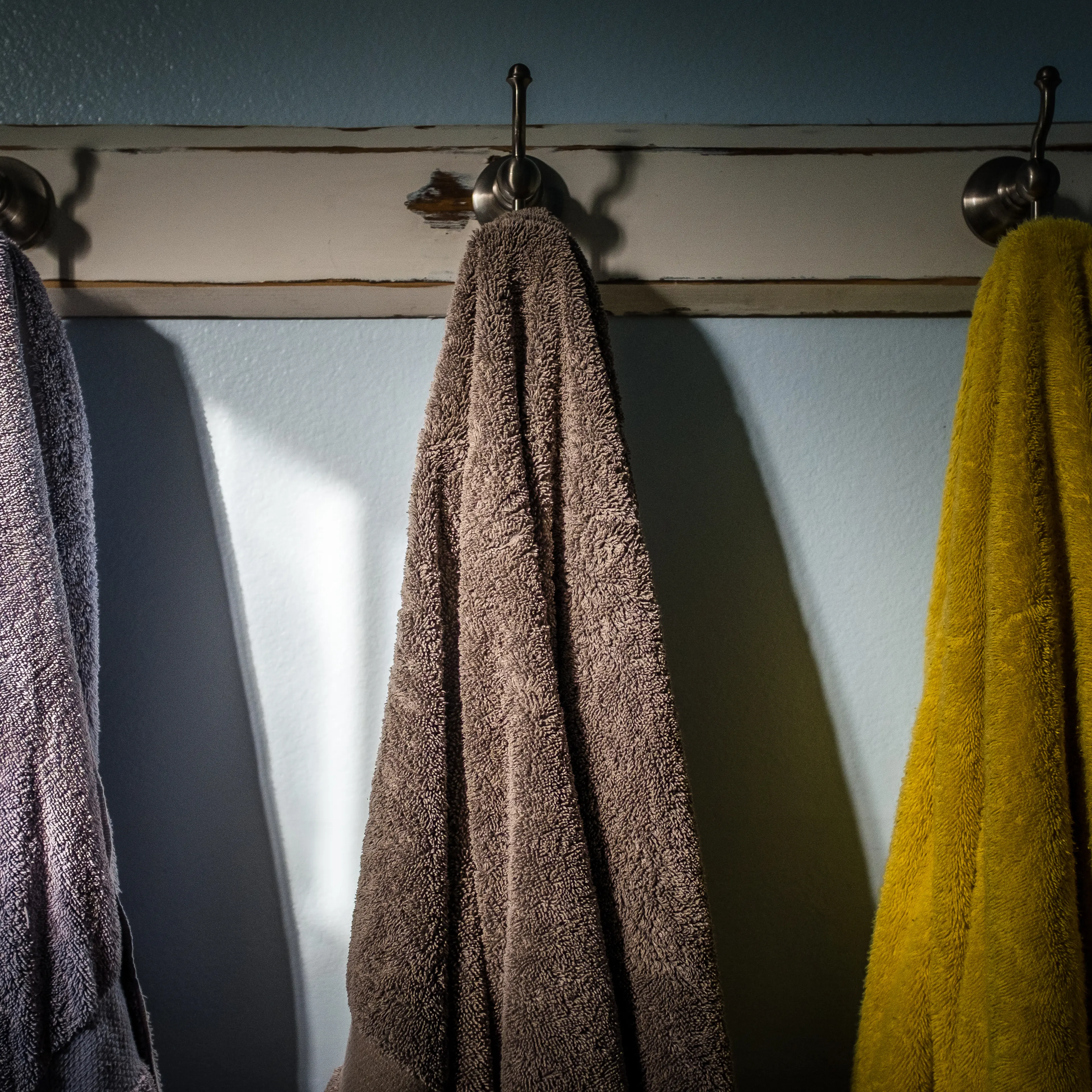 Towels Hanging On Hook Against Wall In Bathroom