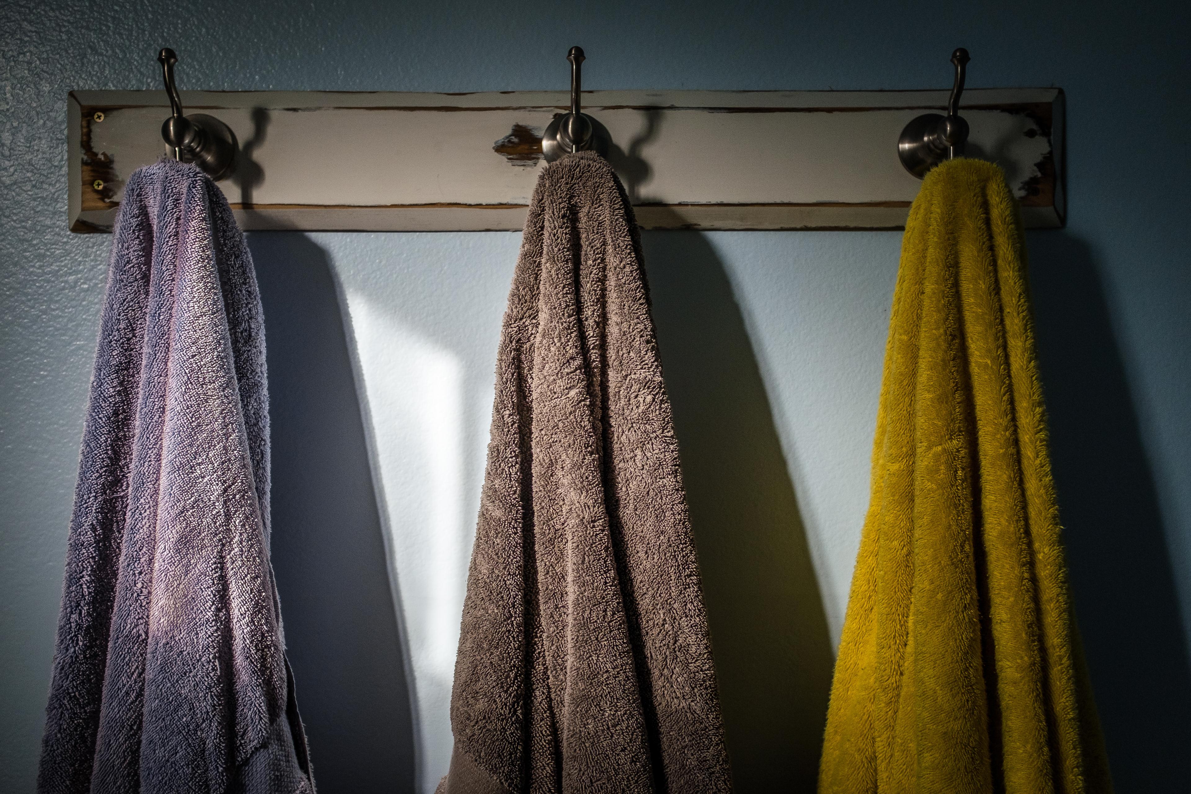 Towels Hanging On Hook Against Wall In Bathroom