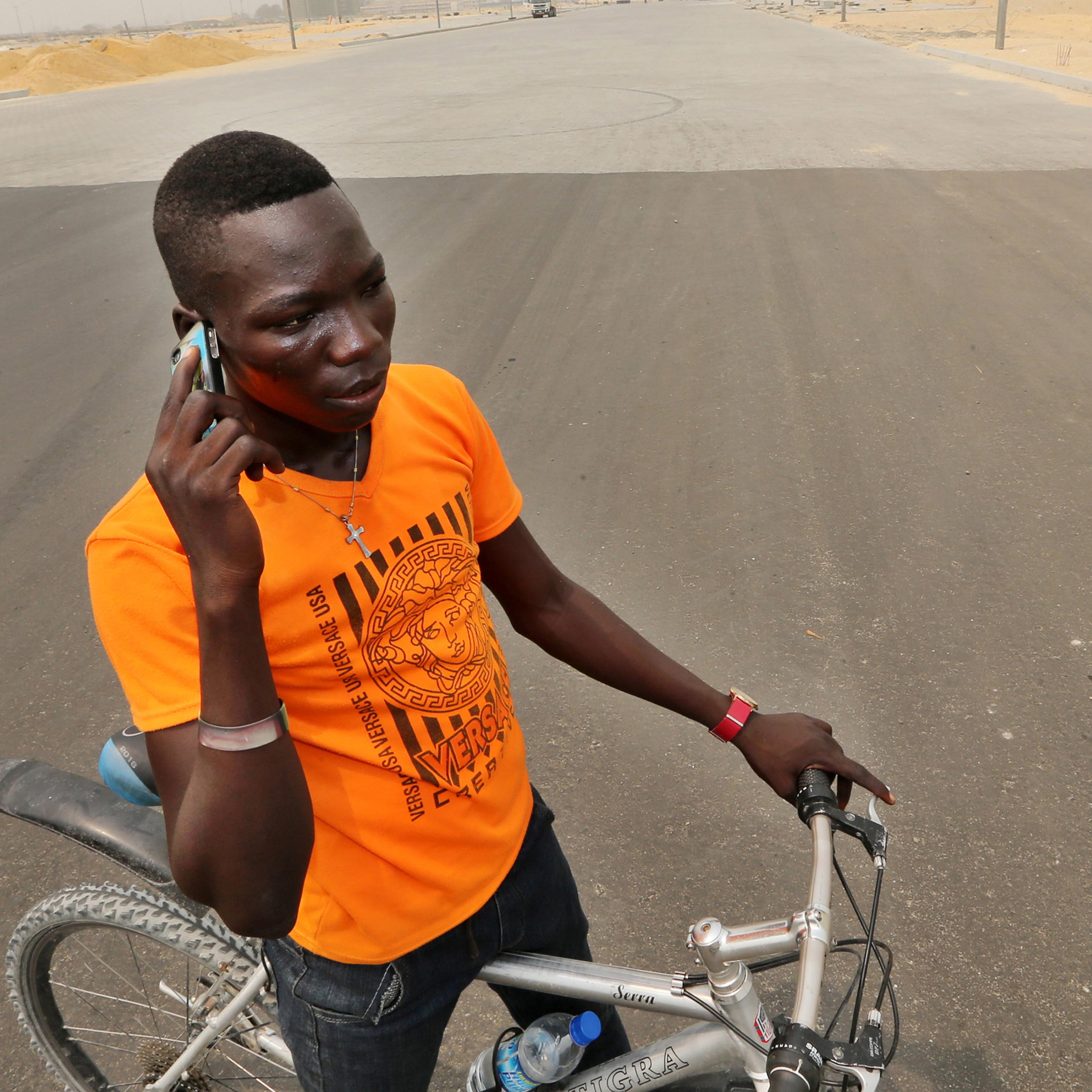 A cyclist stops to make a mobile phone call on a newly surfaced boulevard at the Eko Atlantic City site, developed by Eko Atlantic, near Victoria Island in Lagos, Nigeria on Feb. 12, 2016.