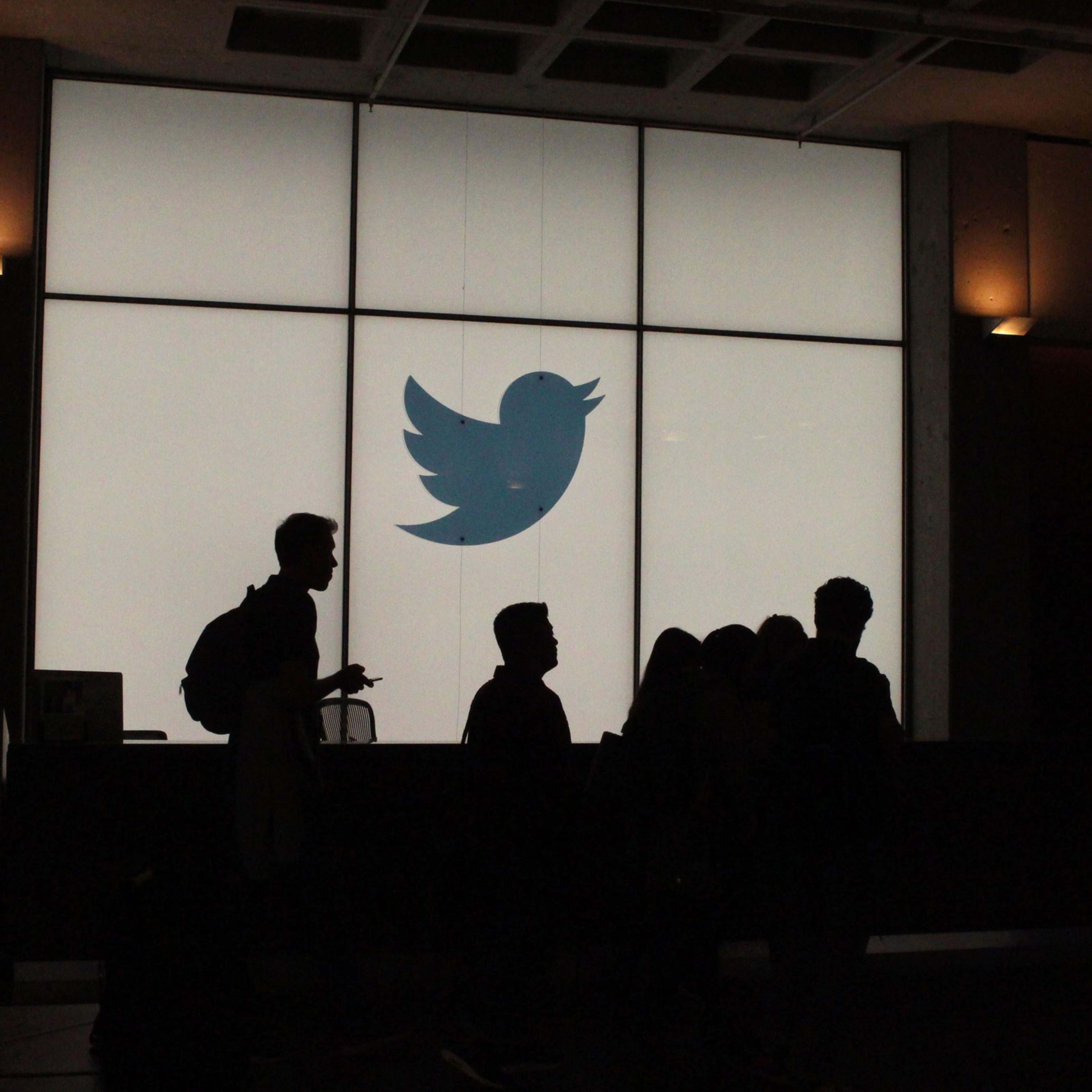 Employees walk past a lighted Twitter logo as they leave the company's headquarters in San Francisco on Aug. 13, 2019.
