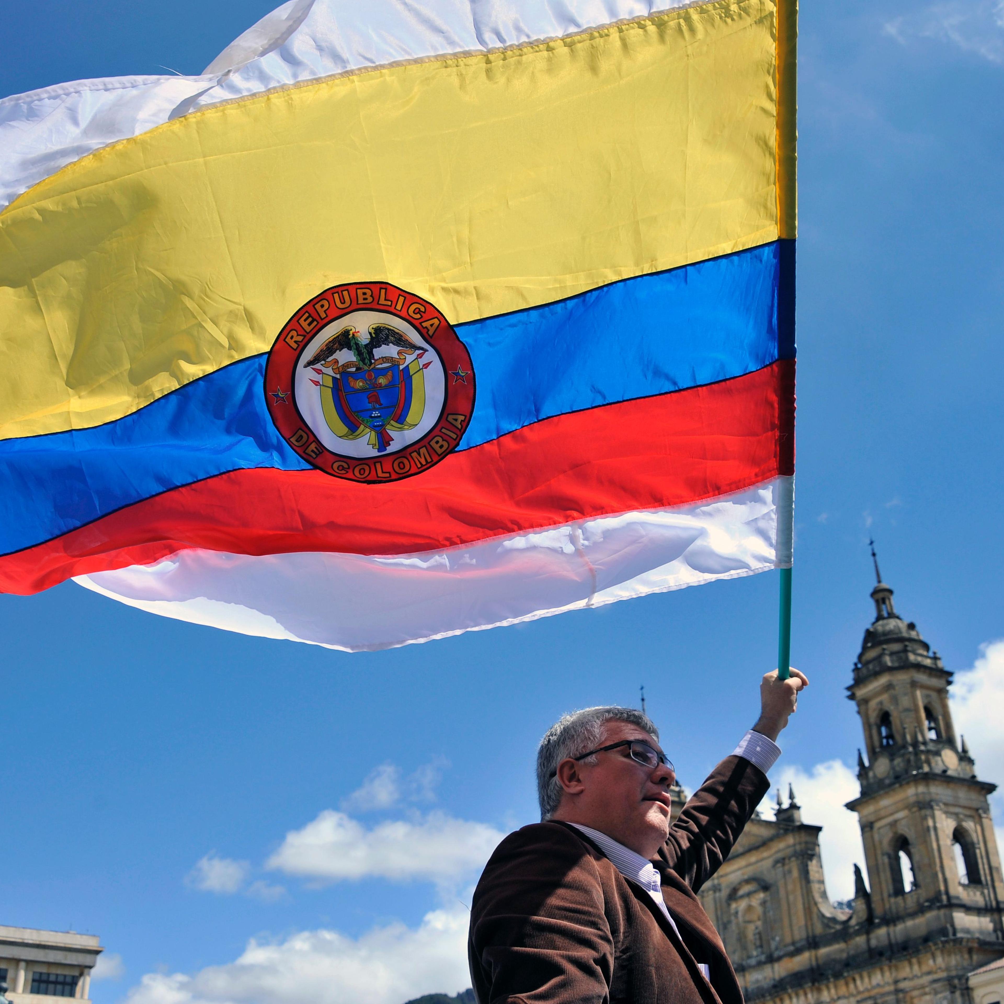 A man holds a Colombian national flag with white stripes during a demo to demand the immediate endorsement of the new peace agreement between the Colombian government and the FARC guerrilla outside the Colombian Congress in Bogota, on November 30, 2016.