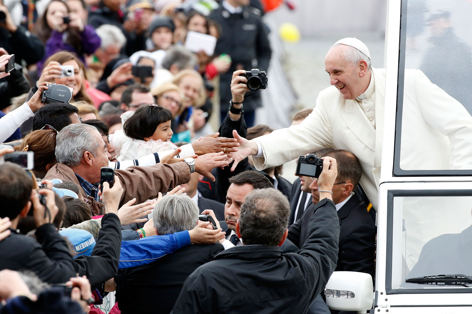 Pope Francis reaches out to greet the faithful as he arrives to lead his Wednesday general audience in Saint Peter's Square at the Vatican March 26, 2014.