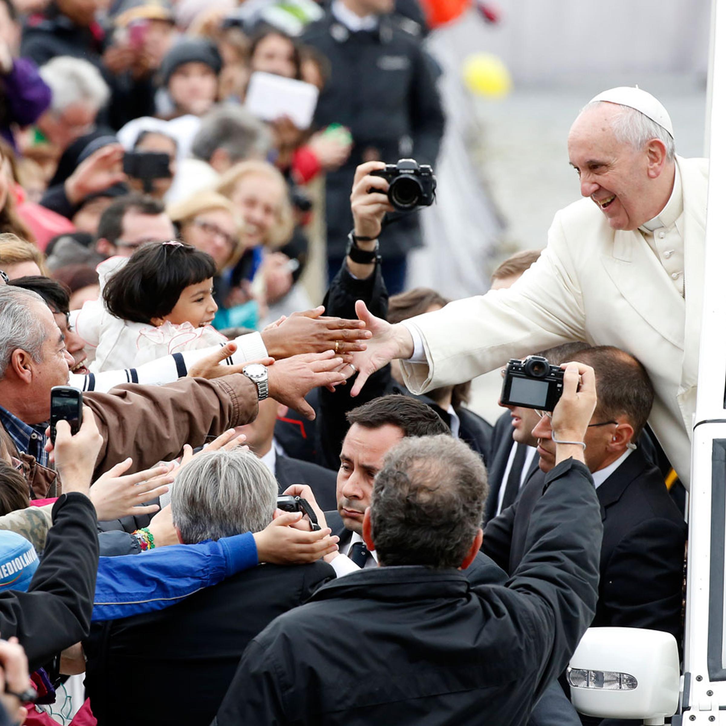 Pope Francis reaches out to greet the faithful as he arrives to lead his Wednesday general audience in Saint Peter's Square at the Vatican March 26, 2014.