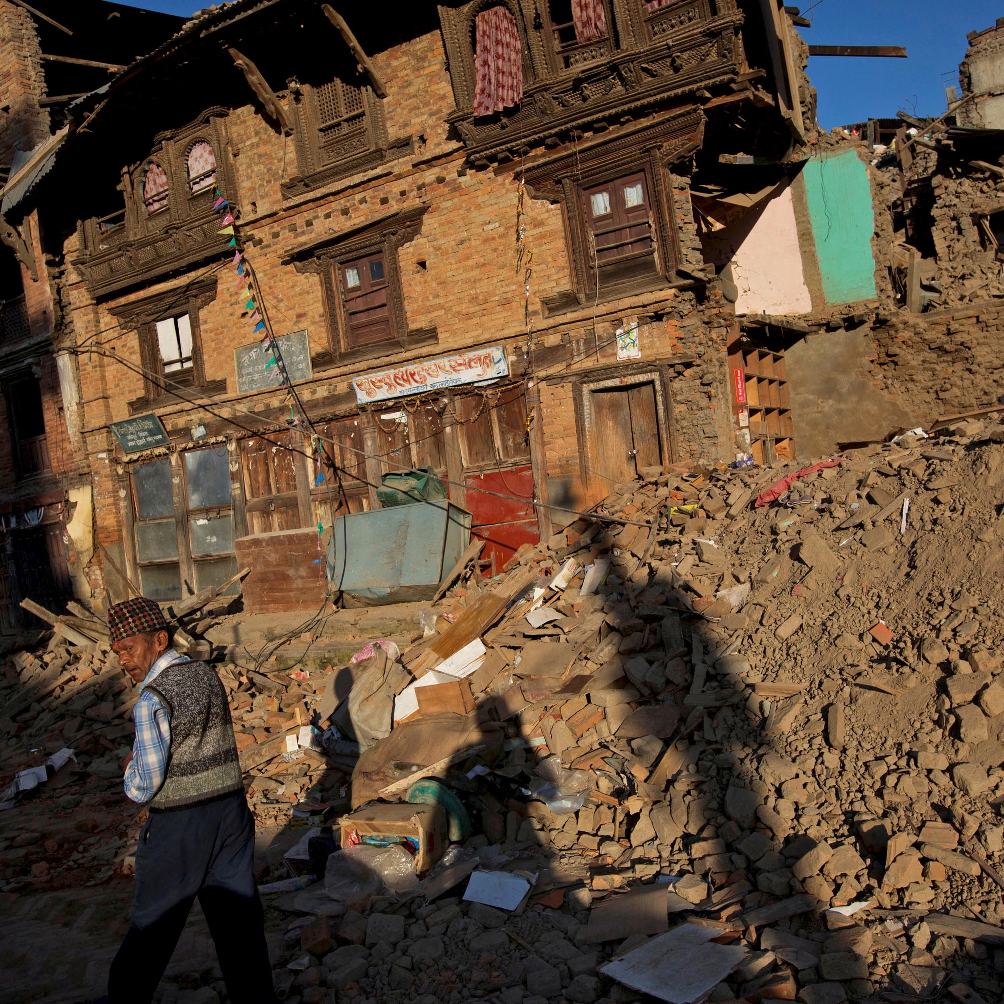 An earthquake victim walks along a street near collapsed houses in Sankhu, on the outskirts of Kathmandu