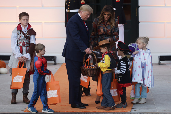 U.S. President Donald Trump and first lady Melania Trump hand out candy to children as they trick-or-treat during a Halloween at the White House event at the South Portico of the White House in Washington, DC on October 28, 2019.