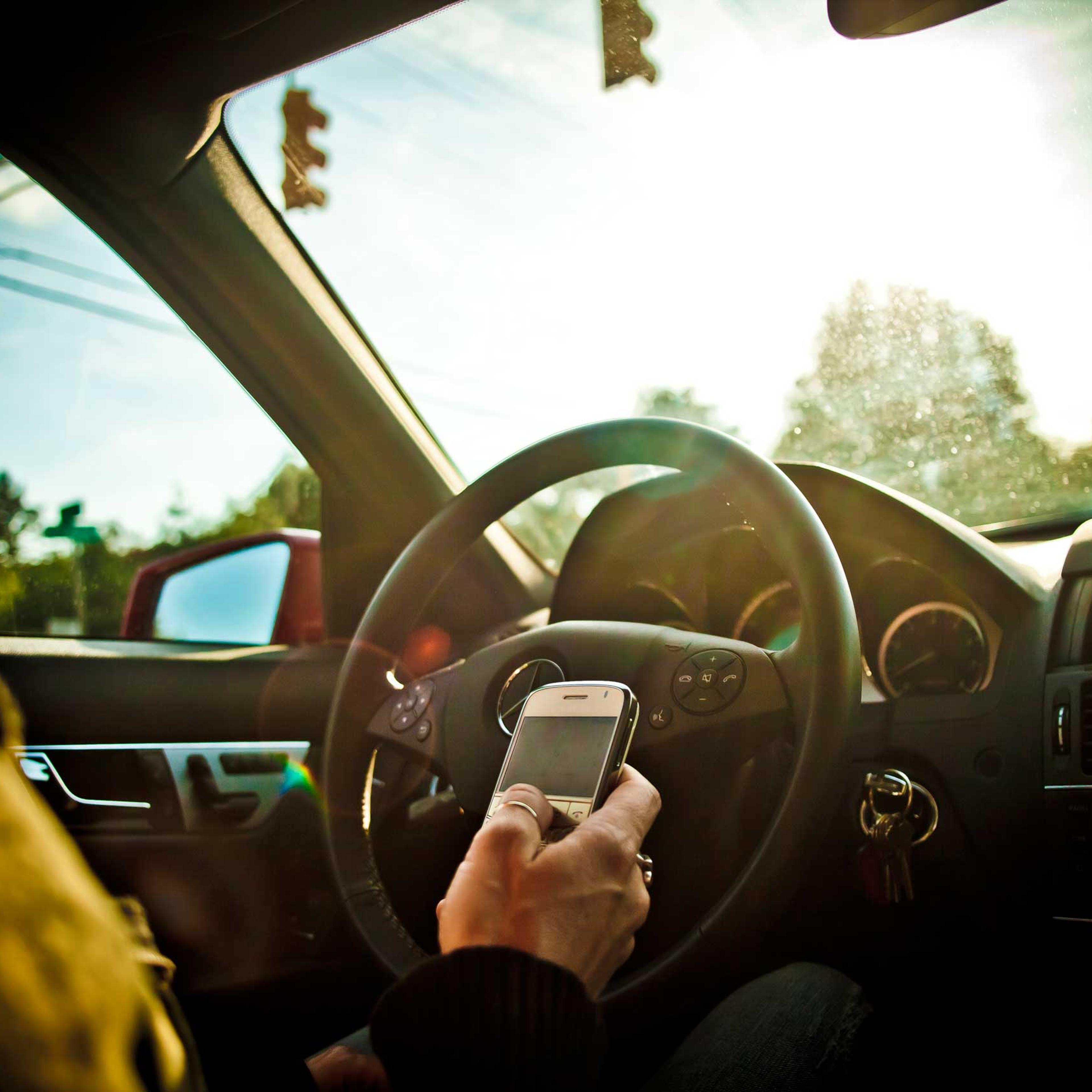 A stock image of a woman texting while driving a car