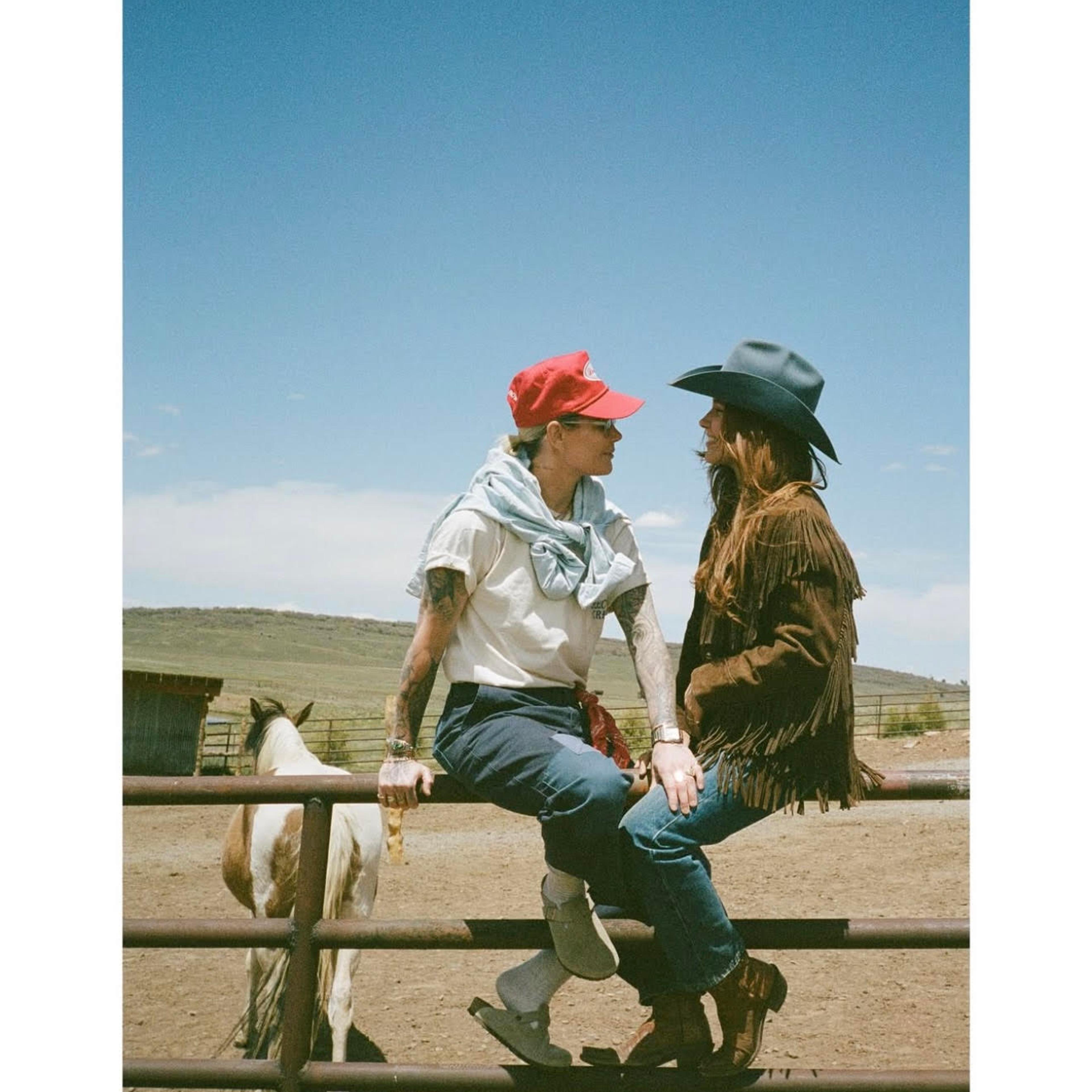 Sophia Bush and Ashlyn Harris sitting together on a fence.