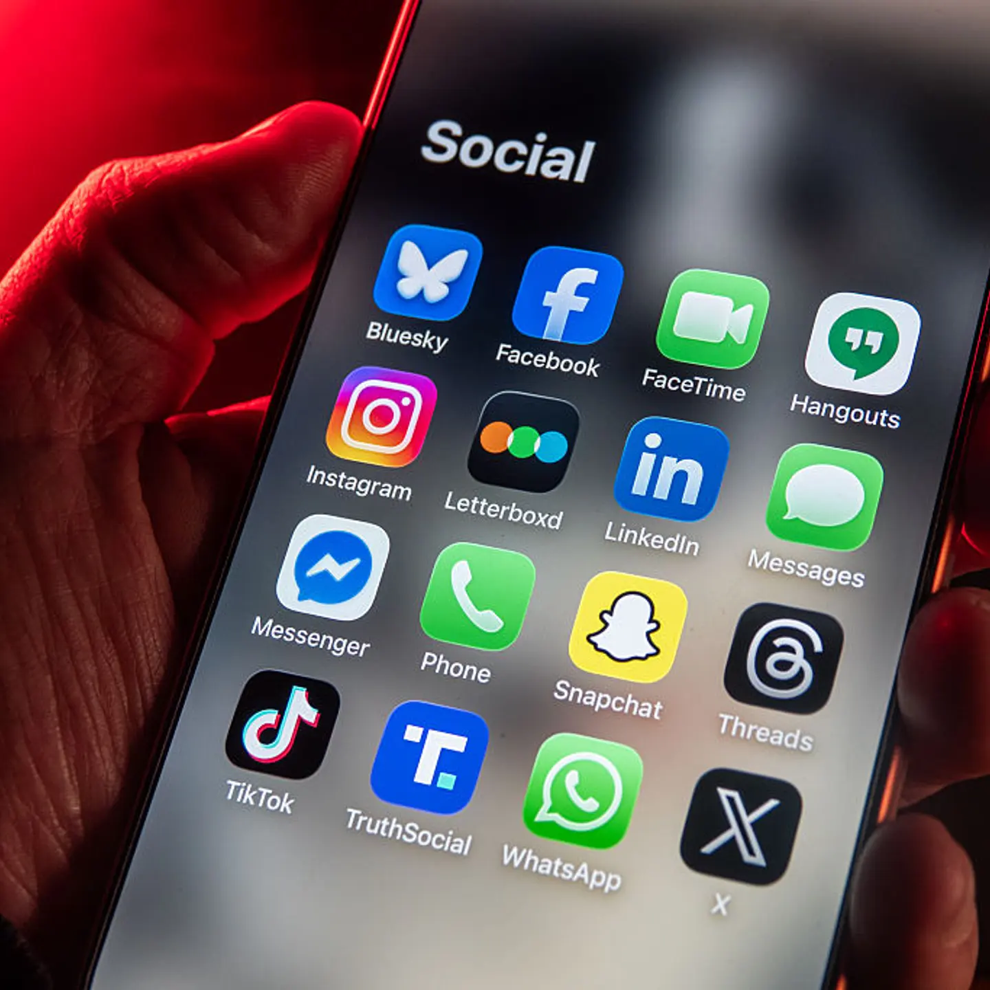 In this photo illustration, a man holds an iPhone screen displaying various social media and messaging apps in Bath, England, on Jan. 25, 2026.