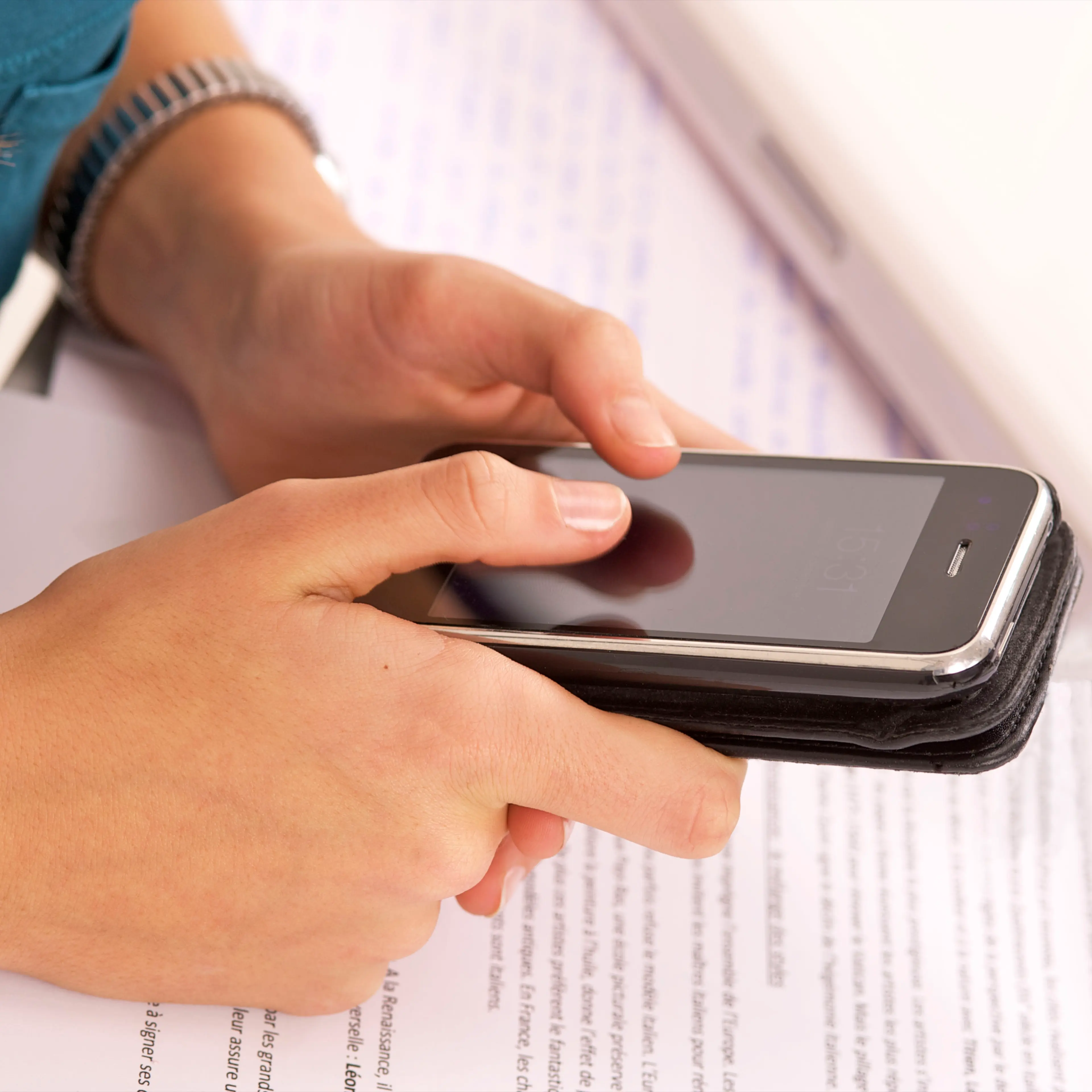 girl using cell phone near textbooks