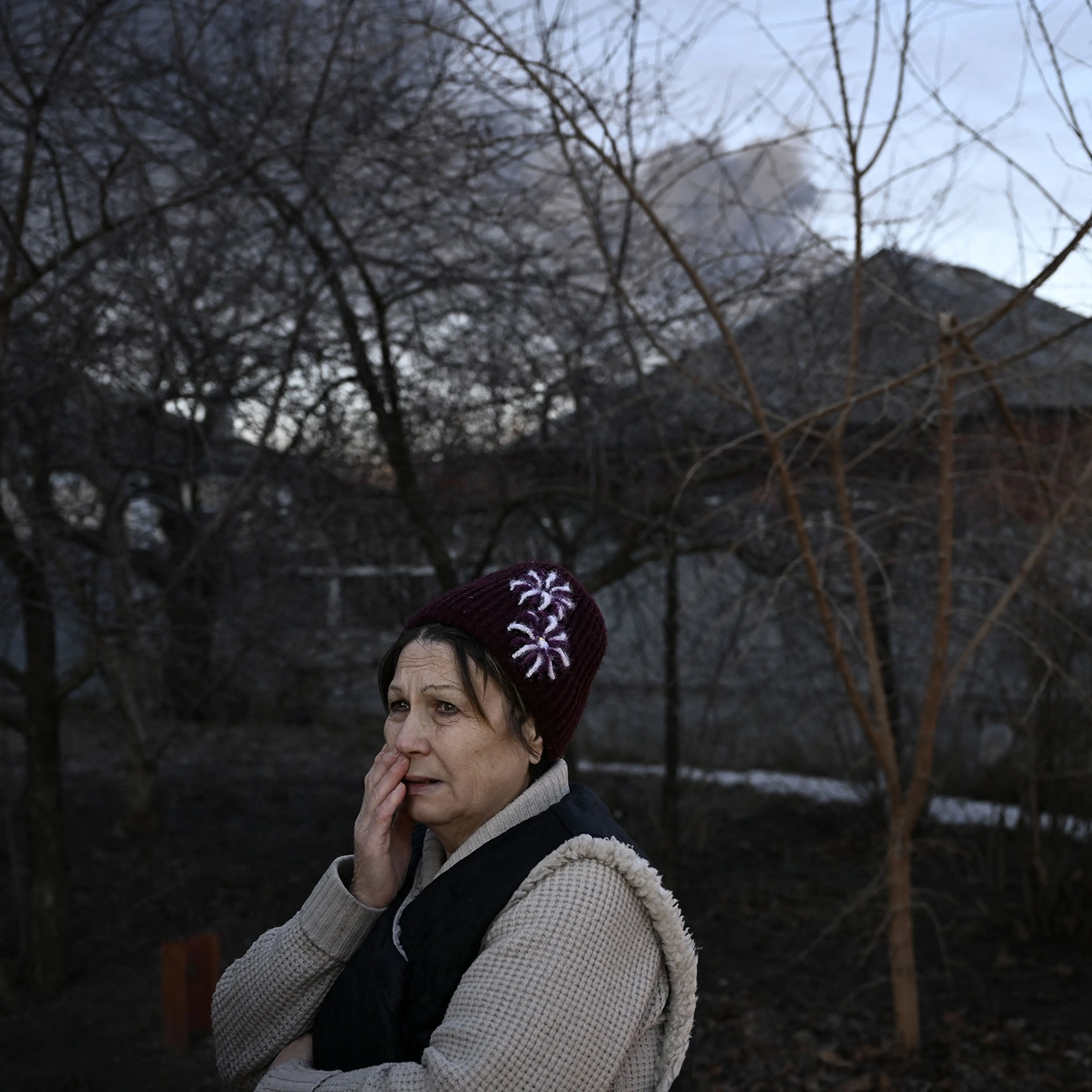 A woman stands in a street as black smoke rises from a military airport in Chuguyev on Feb. 24.