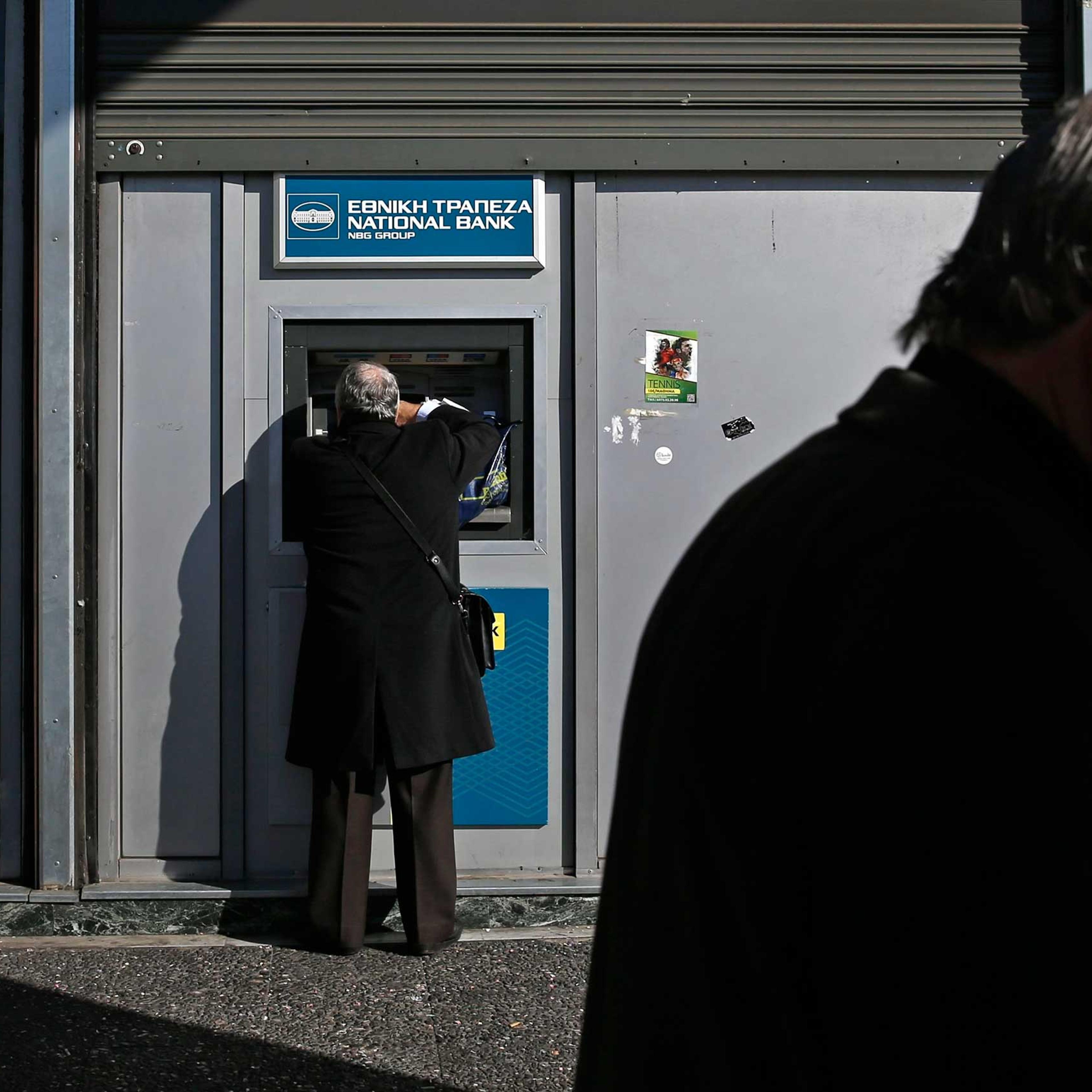 A man makes a transaction at an ATM outside a National Bank of Greece branch in Athens, Feb. 19, 2015.