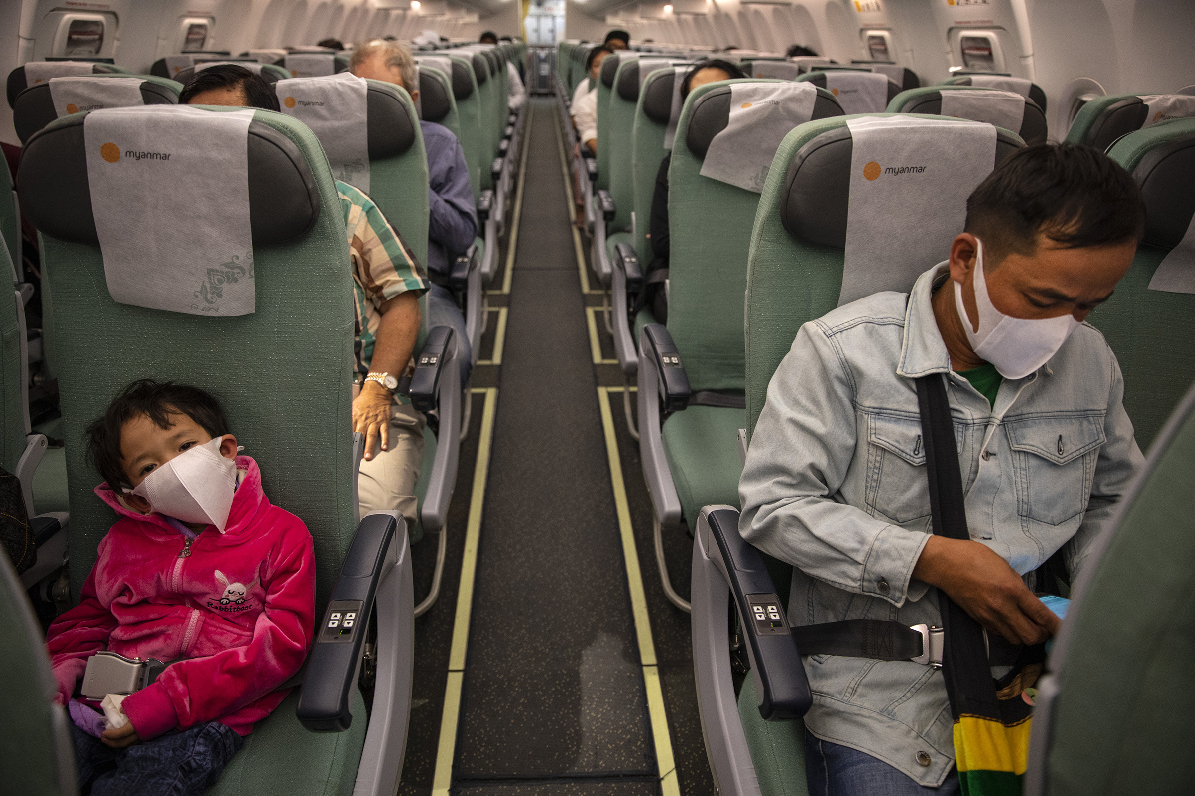 Passengers wear masks on a Myanmar National airlines flight from Yangon to Suvarnabhumi International airport on March 04