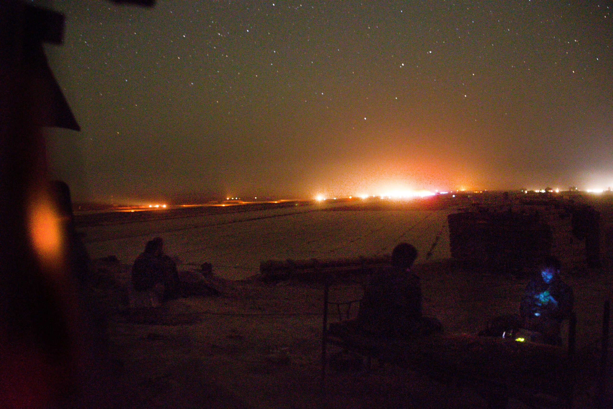 Syrian soldiers guarding the south-eastern front of the runway at Deir-ez Zor’s airport watch as it lights up in preparation for a landing. Military flights that land at the base have become the only way in and out of the government-controlled parts of Deir ez-Zor. The nightly arrival of cargo planes transport munitions, food and medical supplies to the government held parts of the city, May 20, 2015.