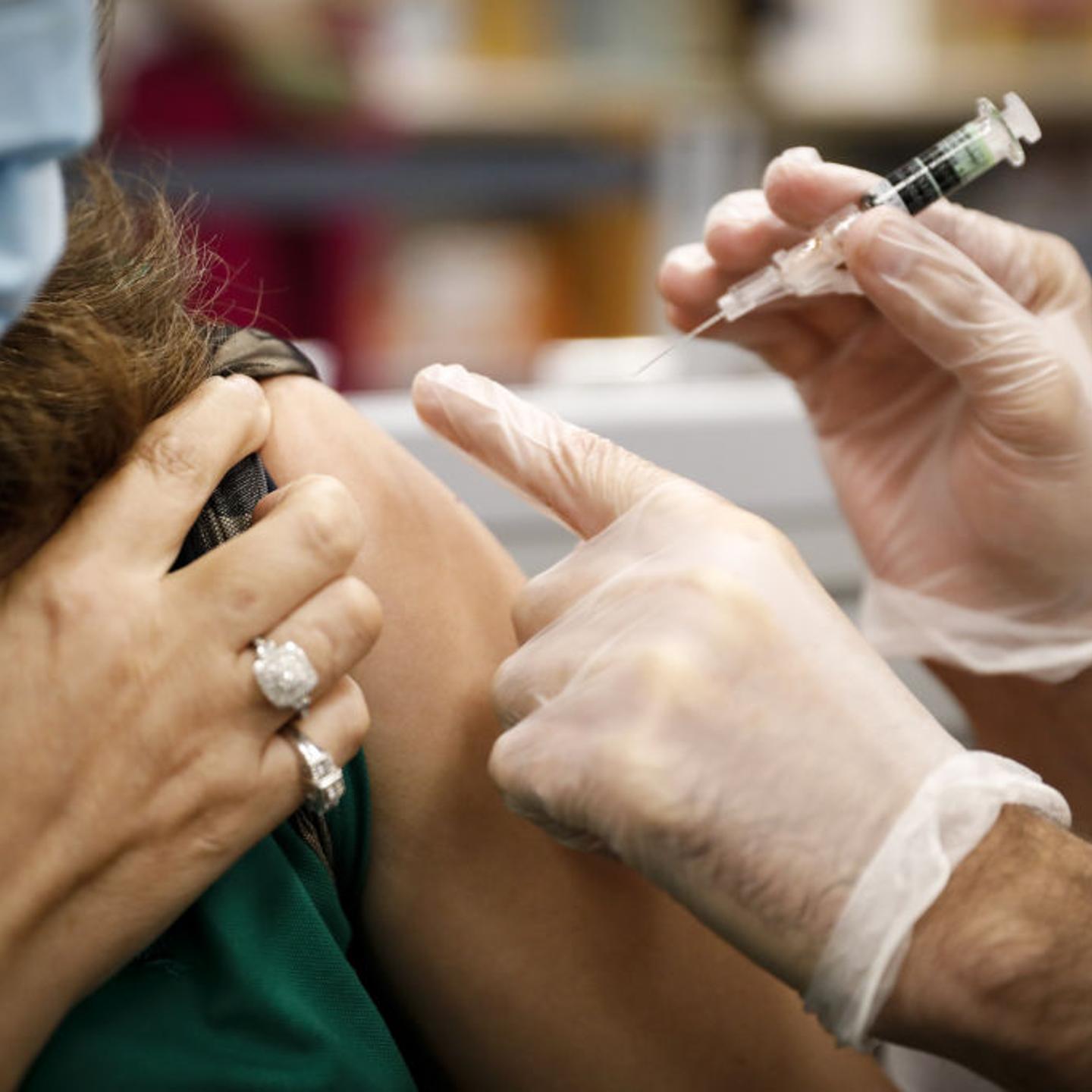 A pharmacist administers a free flu shot vaccine to a customer.