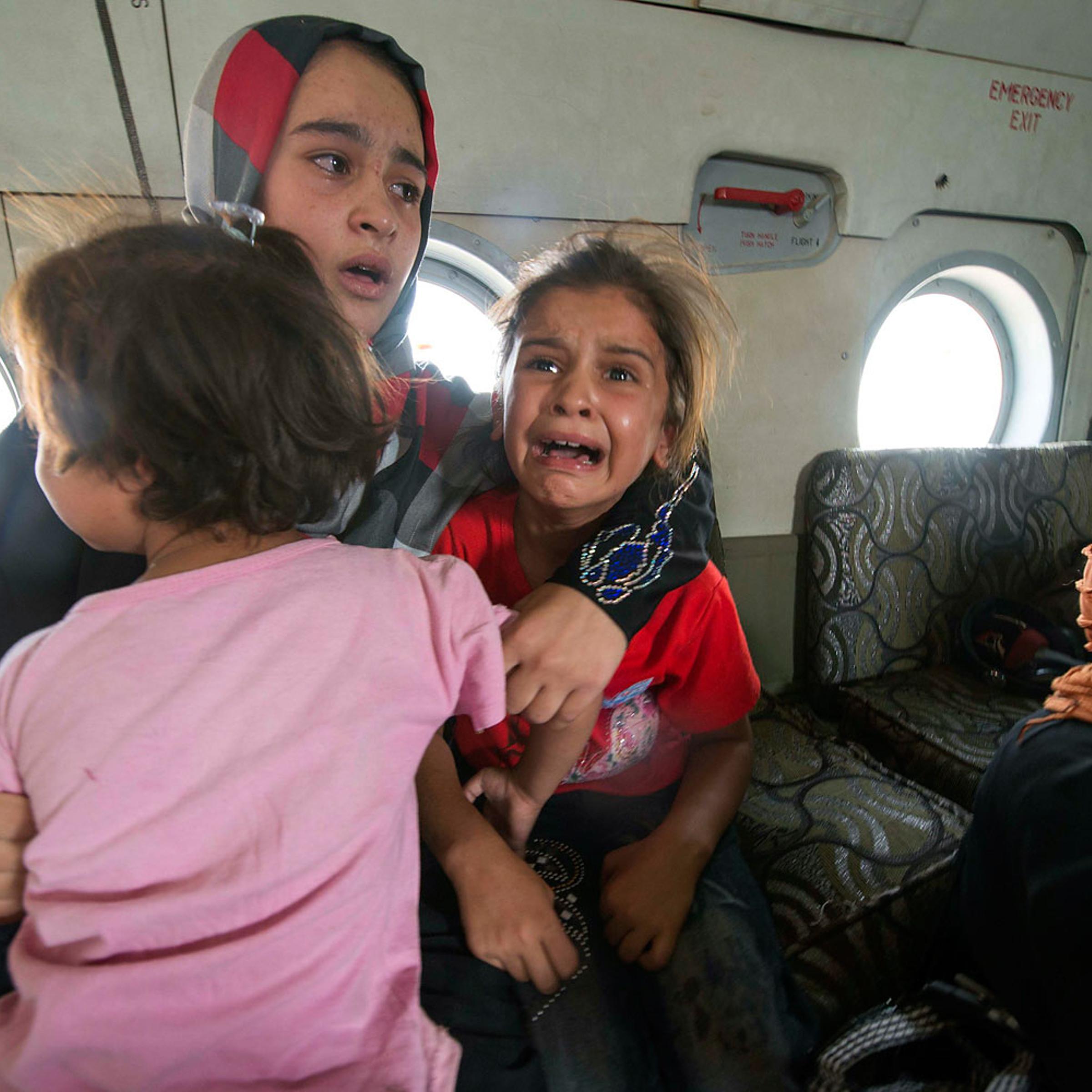 A woman and children react in a military helicopter after being evacuated by Iraqi forces from Amerli