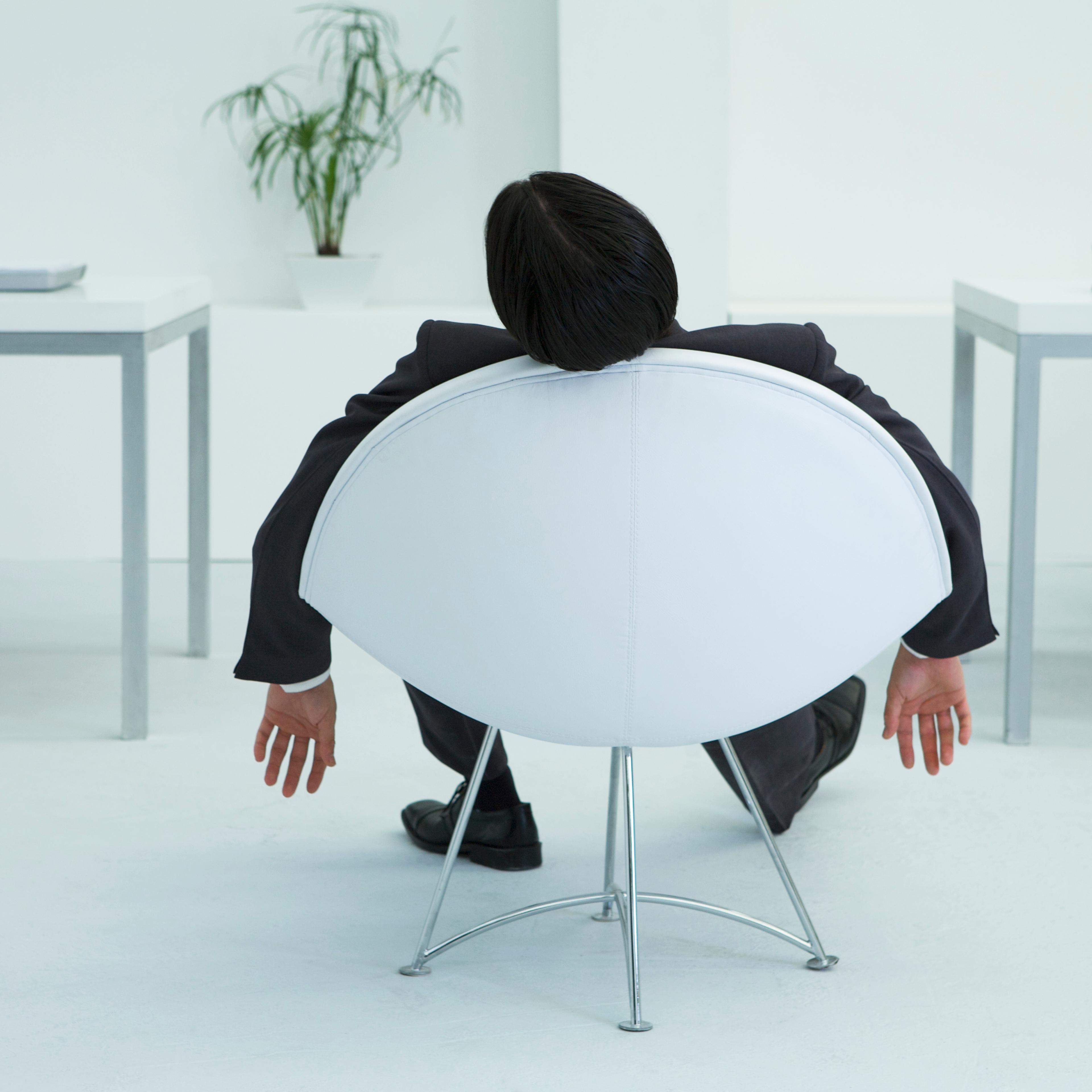 Businessman napping in chair in office, rear view TIME health stock