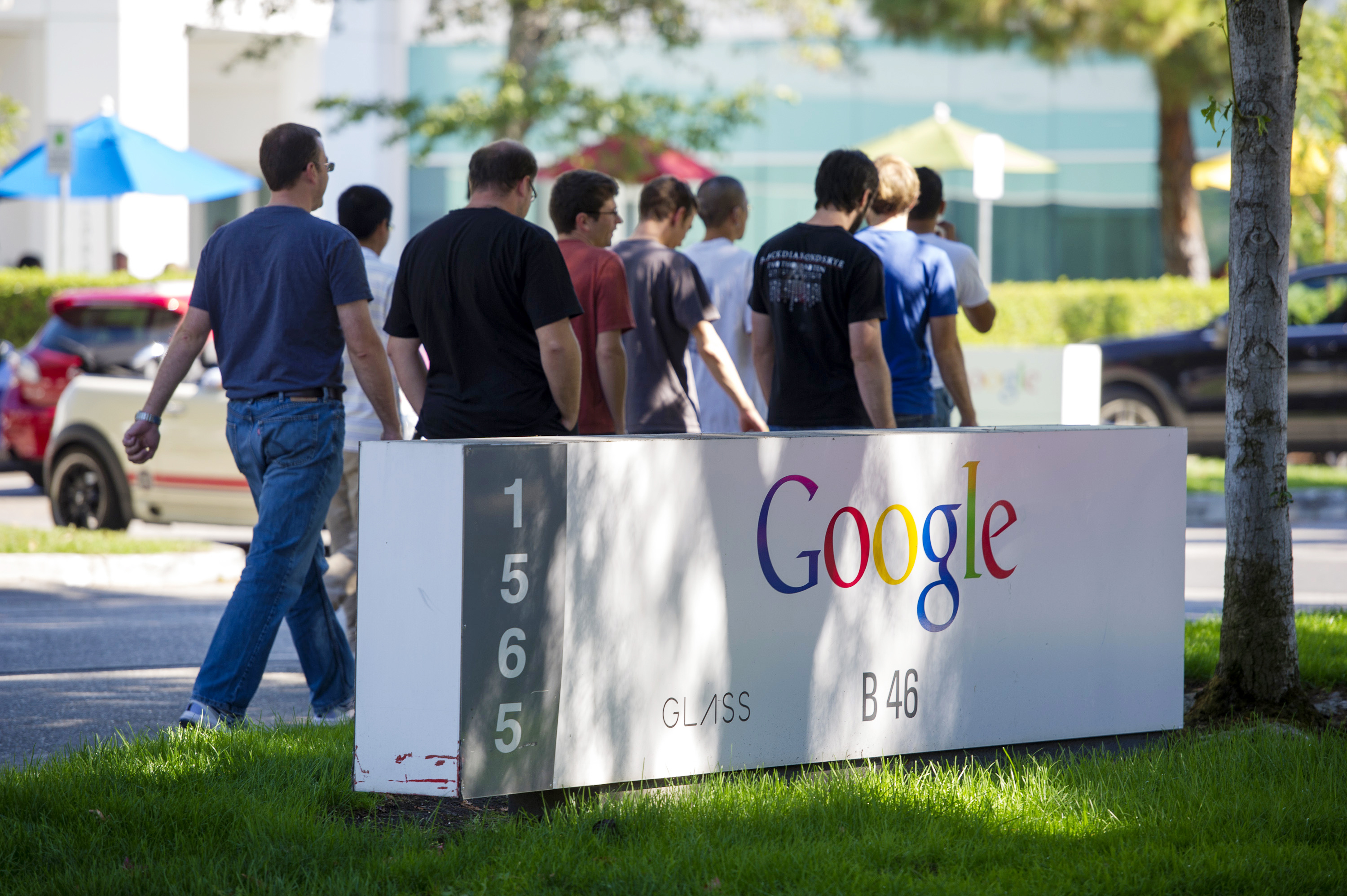 Pedestrians walk past Google Inc. signage displayed in front of the company's headquarters in Mountain View, Calif. on Sept. 27, 2013.