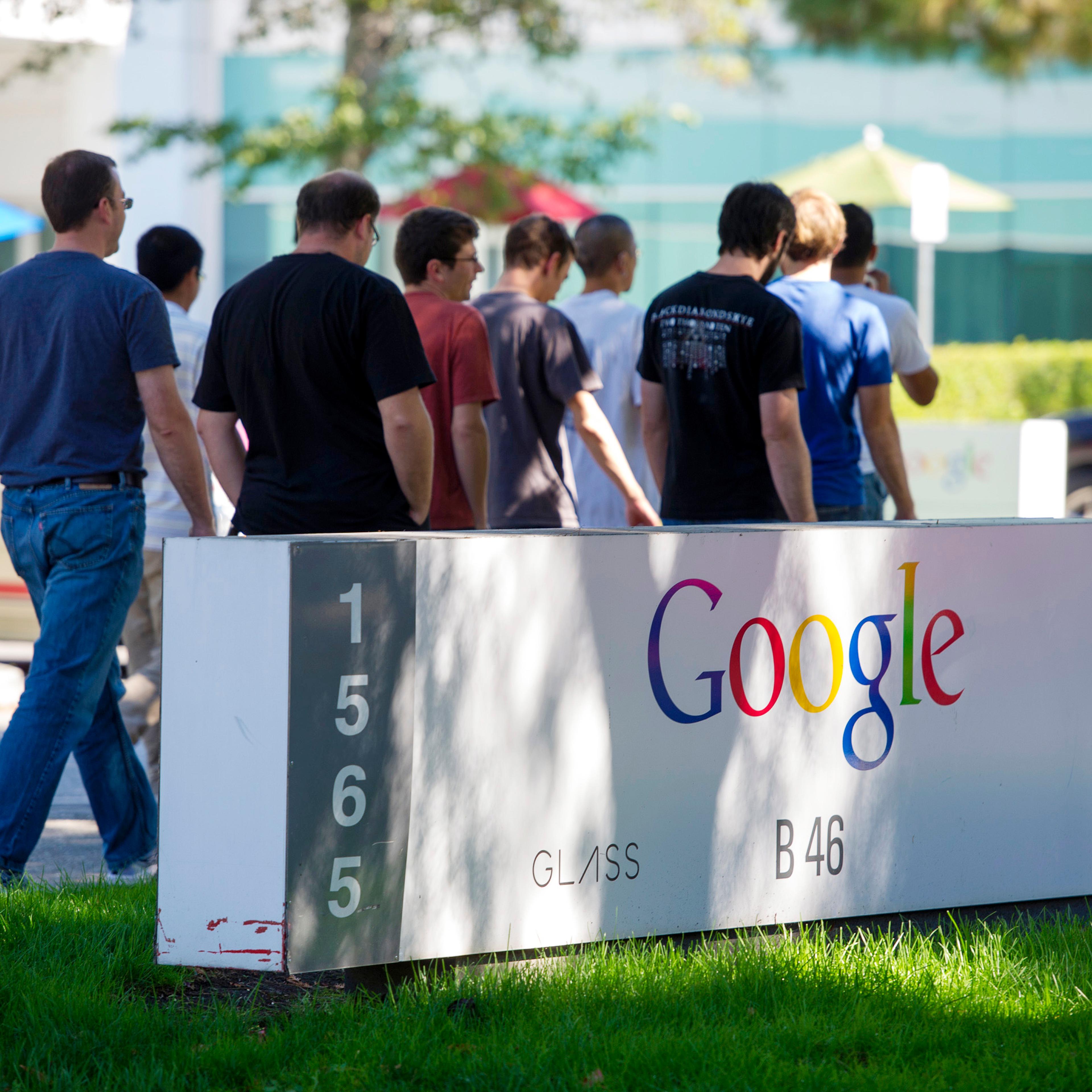 Pedestrians walk past Google Inc. signage displayed in front of the company's headquarters in Mountain View, Calif. on Sept. 27, 2013.