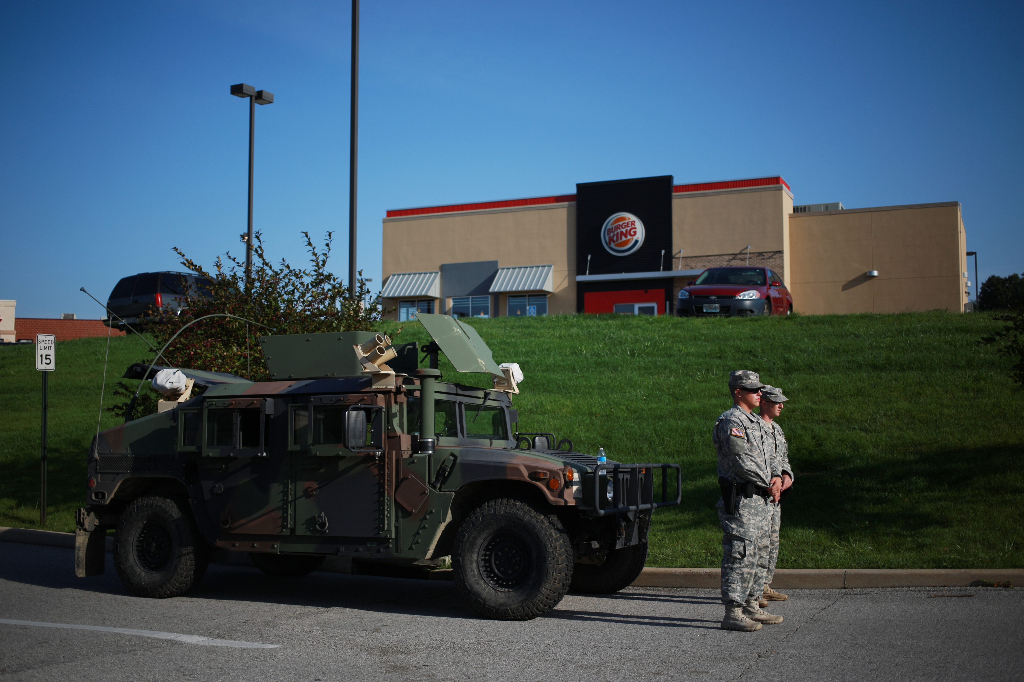 Soldiers from the Missouri National Guard stand in front of their Humvee vehicle outside a Burger King restaurant, operated by Burger King Worldwide Inc., as they man an entrance to a temporary police command center in Ferguson, Missouri, U.S., on Aug. 2