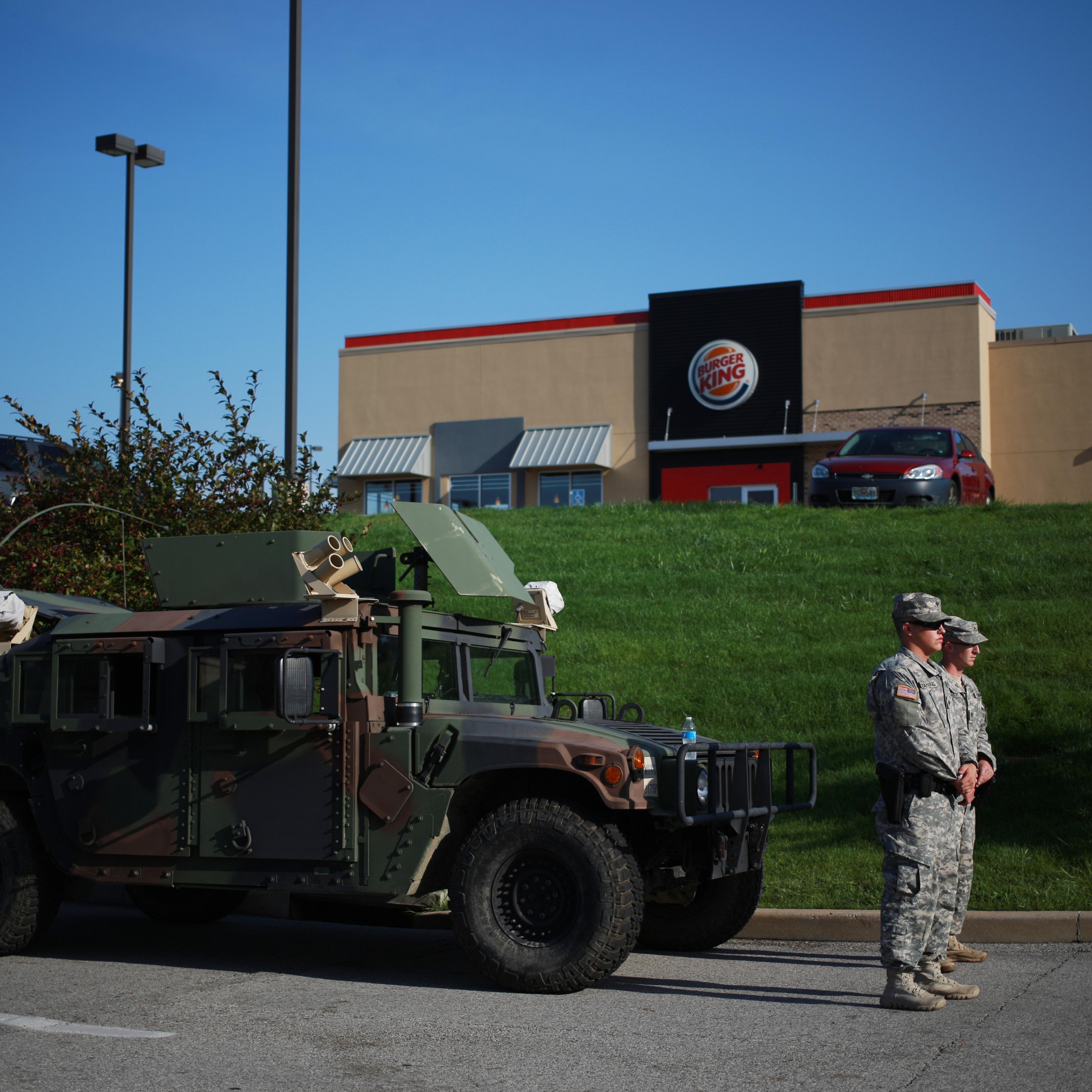 Soldiers from the Missouri National Guard stand in front of their Humvee vehicle outside a Burger King restaurant, operated by Burger King Worldwide Inc., as they man an entrance to a temporary police command center in Ferguson, Missouri, U.S., on Aug. 2