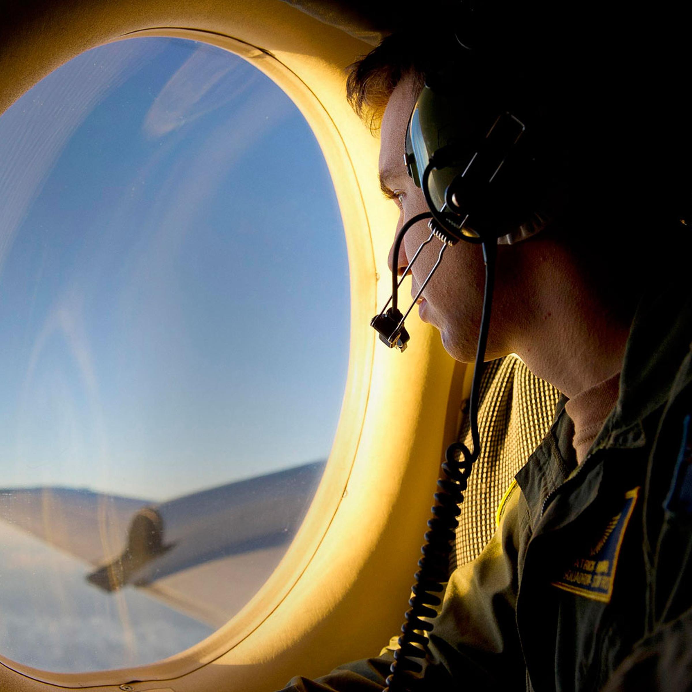 Royal Australian Air Force (RAAF) Airborne Electronics Analyst Sergeant Patrick Manser looks out of an observation window aboard a RAAF AP-3C Orion aircraft during the search in the southern Indian Ocean for debris from the missing Malaysian Airlines fli