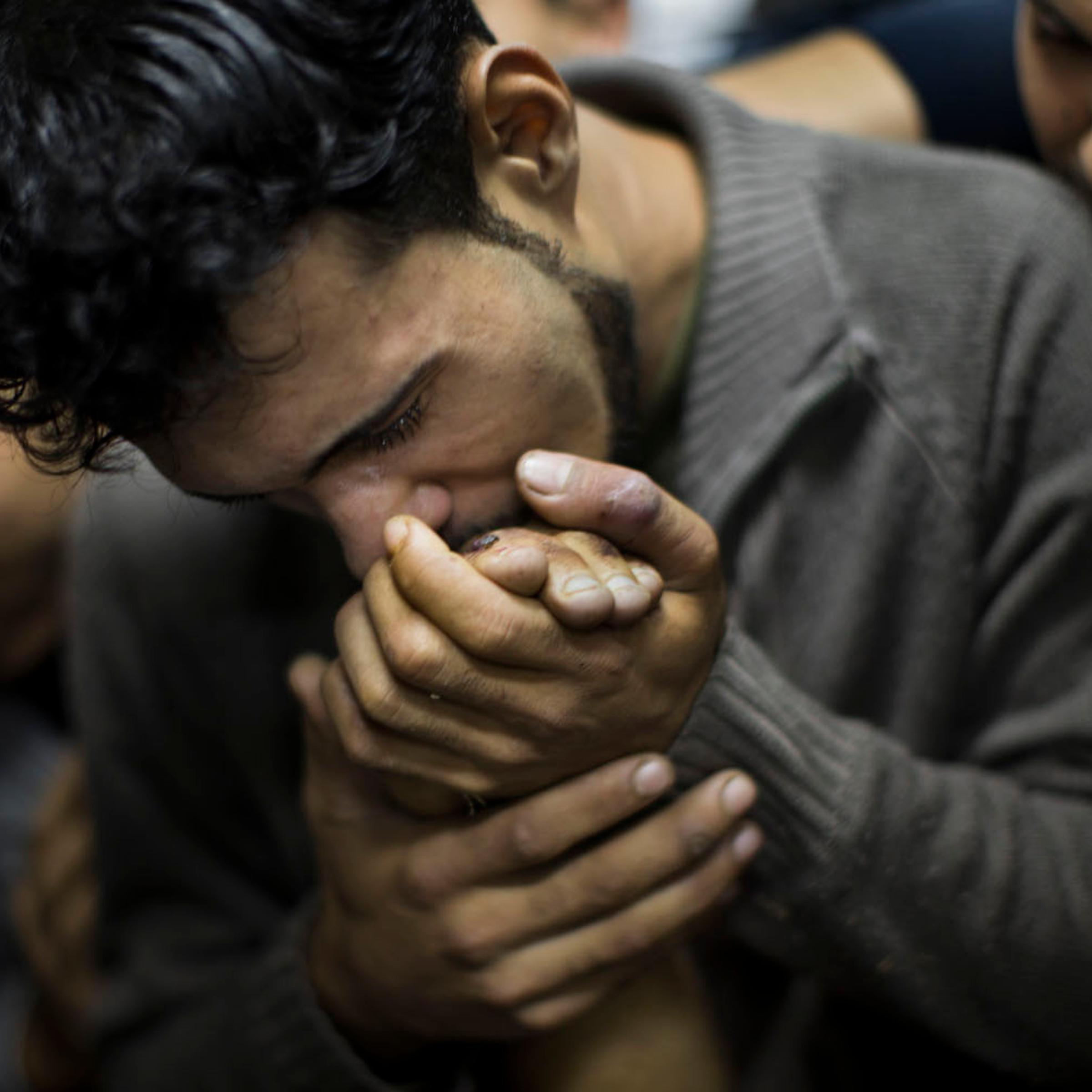Nov. 18, 2012. A Palestinian man kisses the hand of a dead relative in the morgue of Shifa Hospital in Gaza City.