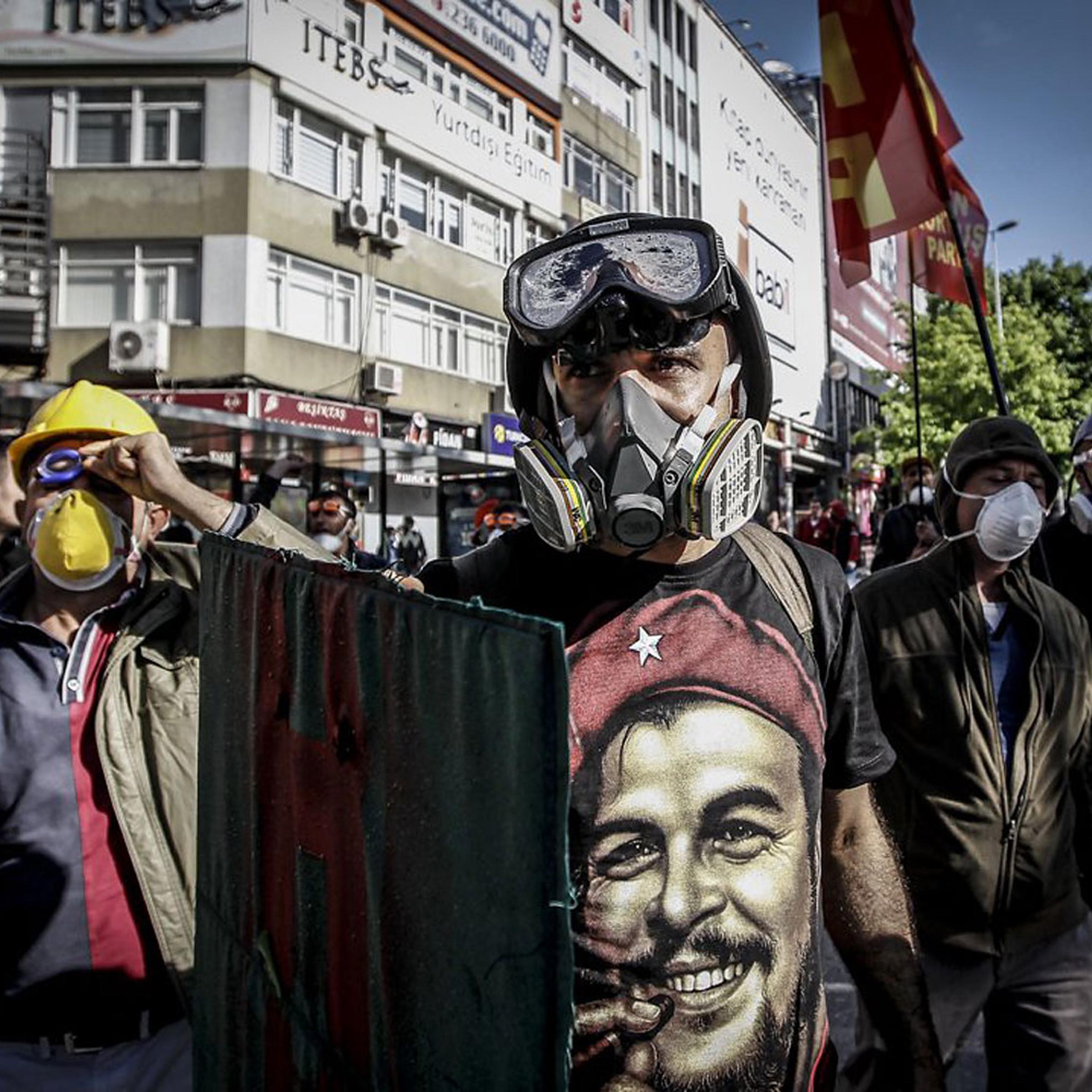 A Turkish protestor wearing a gas mask and a hard hat takes cover during clashes with riot police who prevent demonstrators from reaching Taksim Square in Istanbul for a May Day rally on May 1, 2014.