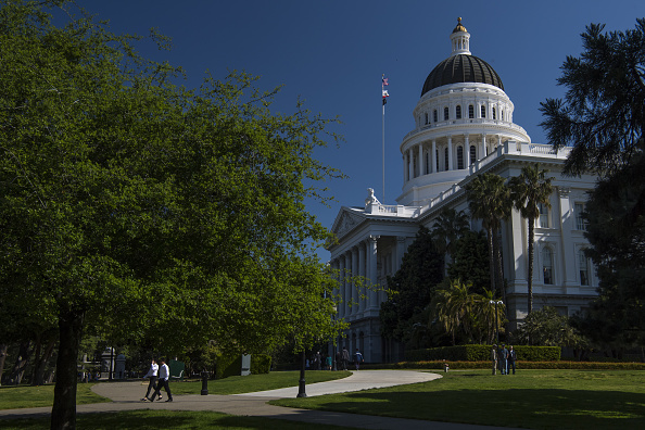 Pedestrians walk past the California State Capitol building in Sacramento, California, U.S., on Thursday, March 30, 2017.