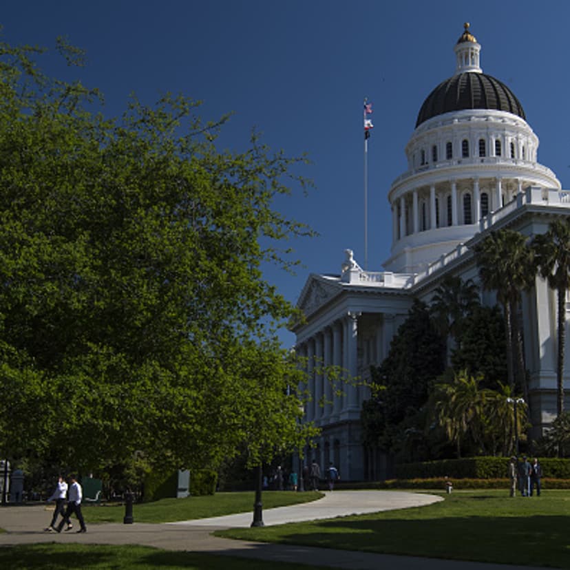 Pedestrians walk past the California State Capitol building in Sacramento, California, U.S., on Thursday, March 30, 2017.