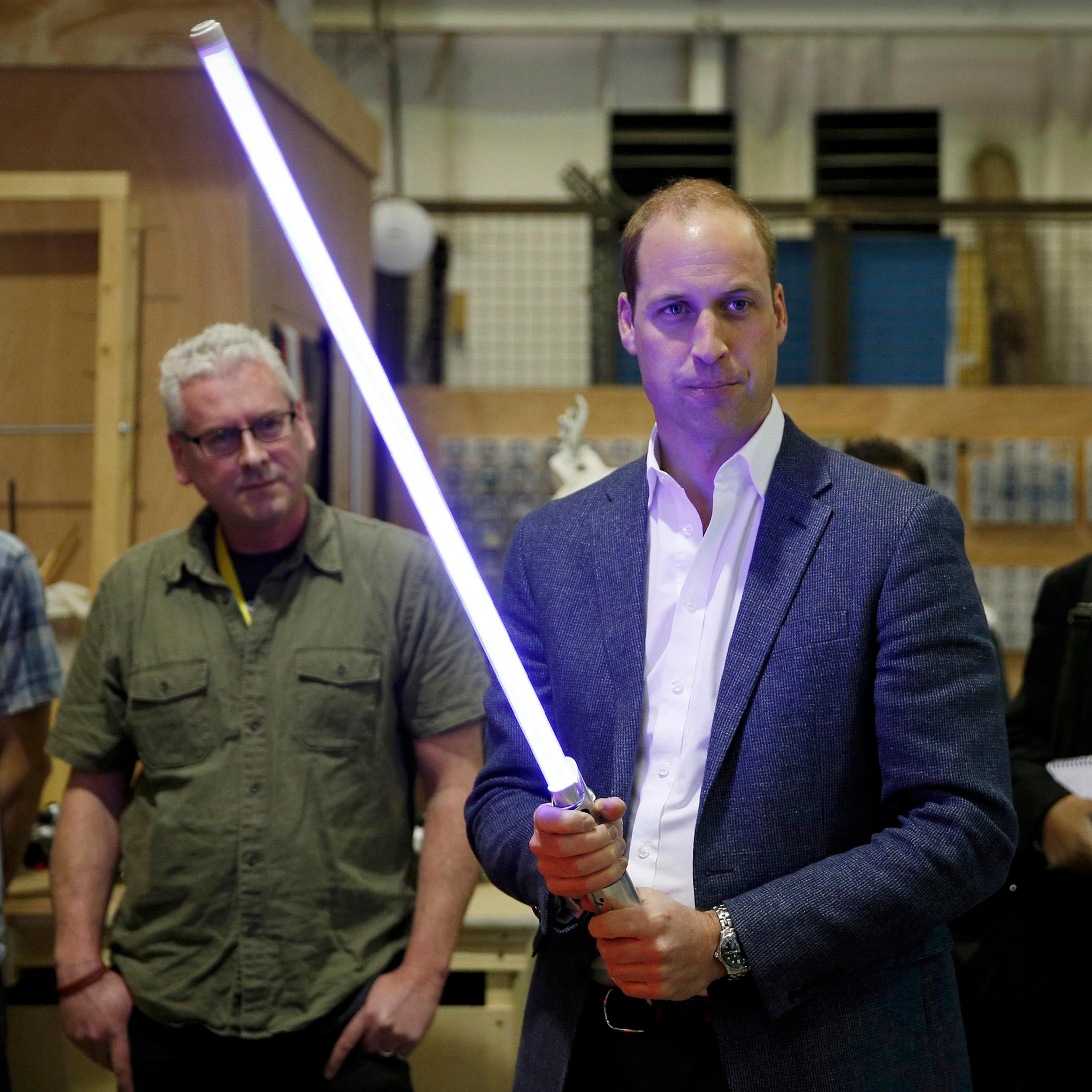 Britain's Prince William holds a light saber during a visit to the Star Wars film set at Pinewood Studios near Iver Heath, west of London, April 19, 2016.